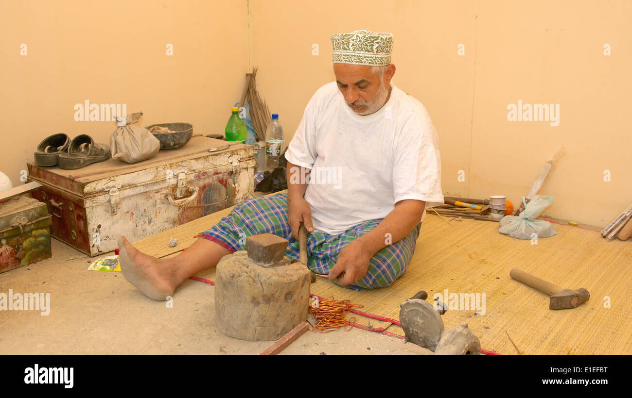 Ein bärtiger omanischen Kupferschmied, tragen eine traditionelle Kuma (GAP), bei der Arbeit in Muscat, in das Sultanat Oman. Stockfoto
