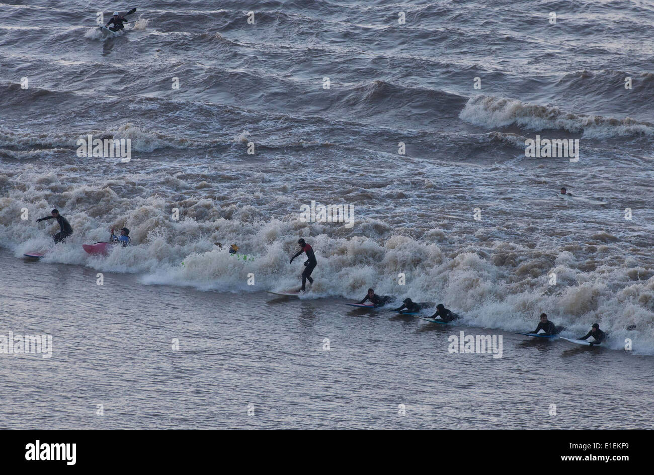 Surfer und Menschen in Kajaks auf die fünf Sterne Severn Bore Welle zu reiten, wie es geht Newnham in Gloucestershire. Stockfoto