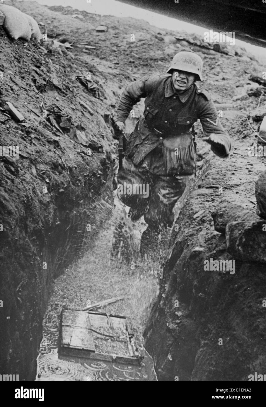 Ein Bote der deutschen Armee überbringt im Juni 1943 an der Front eine wichtige Botschaft. Der Originaltext eines Nazi-Berichts auf der Rückseite lautet: "Messenger! Die Telefonleitung wurde zerstört. Das Funkgerät wird für Artilleriefeuer benutzt. Der Bote wird eingesetzt, um wichtige Befehle zur nächsten Station zu bringen. Der Schrei „Botschafter“ reicht aus, und in den nächsten Sekunden erscheint er vor dem Firmenchef, um den entscheidenden Batte-Befehl zu erhalten. Er weiß, worum es geht; das kniehohe Wasser in den Gräben ist die geringste seiner Hürden.“ Fotoarchiv für Zeitgeschichtee - KEIN KABELDIENST Stockfoto