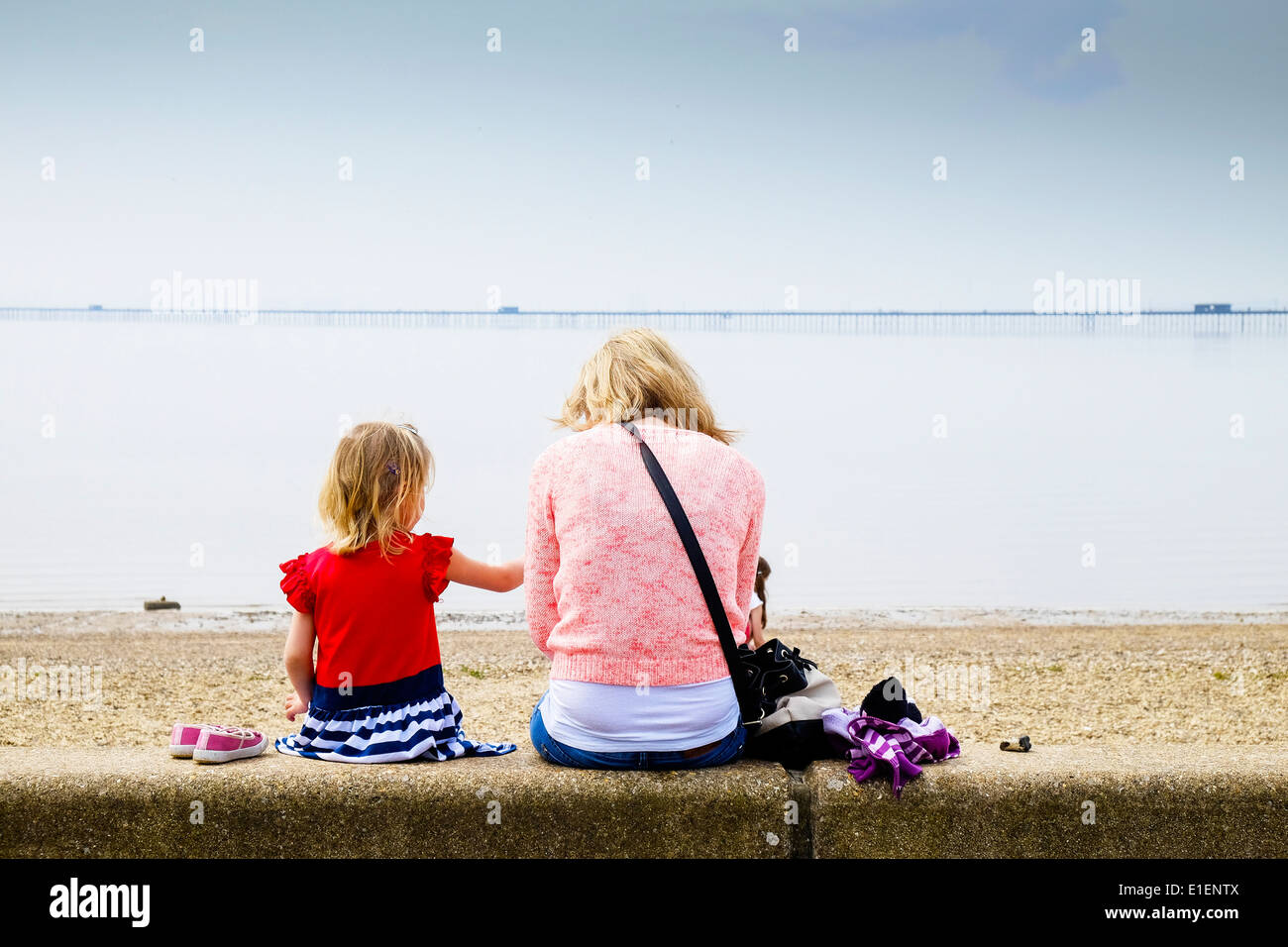 Eine Mutter und ihre Tochter sitzt auf einer Mauer mit Blick auf Jubilee Strand in Southend on Sea. Stockfoto