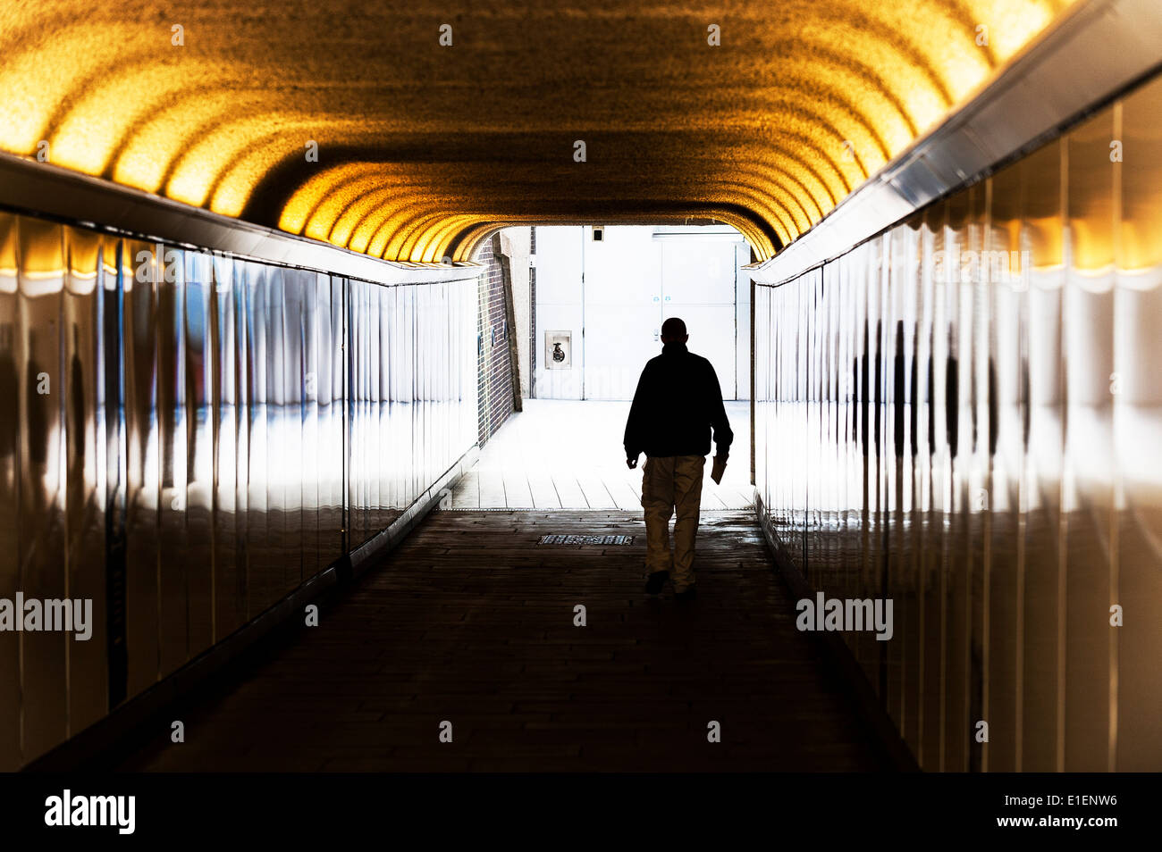 Die Silhouette eines Mannes zu Fuß durch eine Fußgängerunterführung. Stockfoto