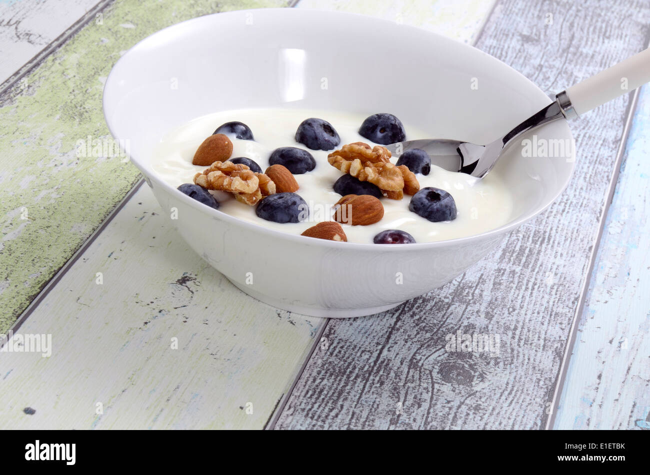 Frischen Joghurt mit Müsli und Beeren in eine Schüssel geben Stockfoto