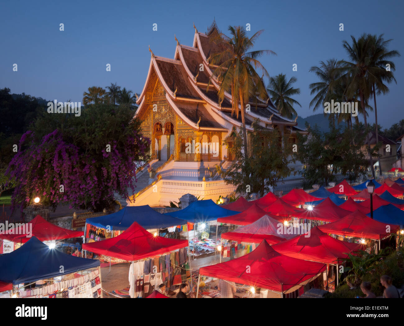 Ein Blick auf den Nachtmarkt von Luang Prabang. Haw Pha Bang (der goldene Saal) erhebt sich im Hintergrund.  Luang Prabang, Laos. Stockfoto