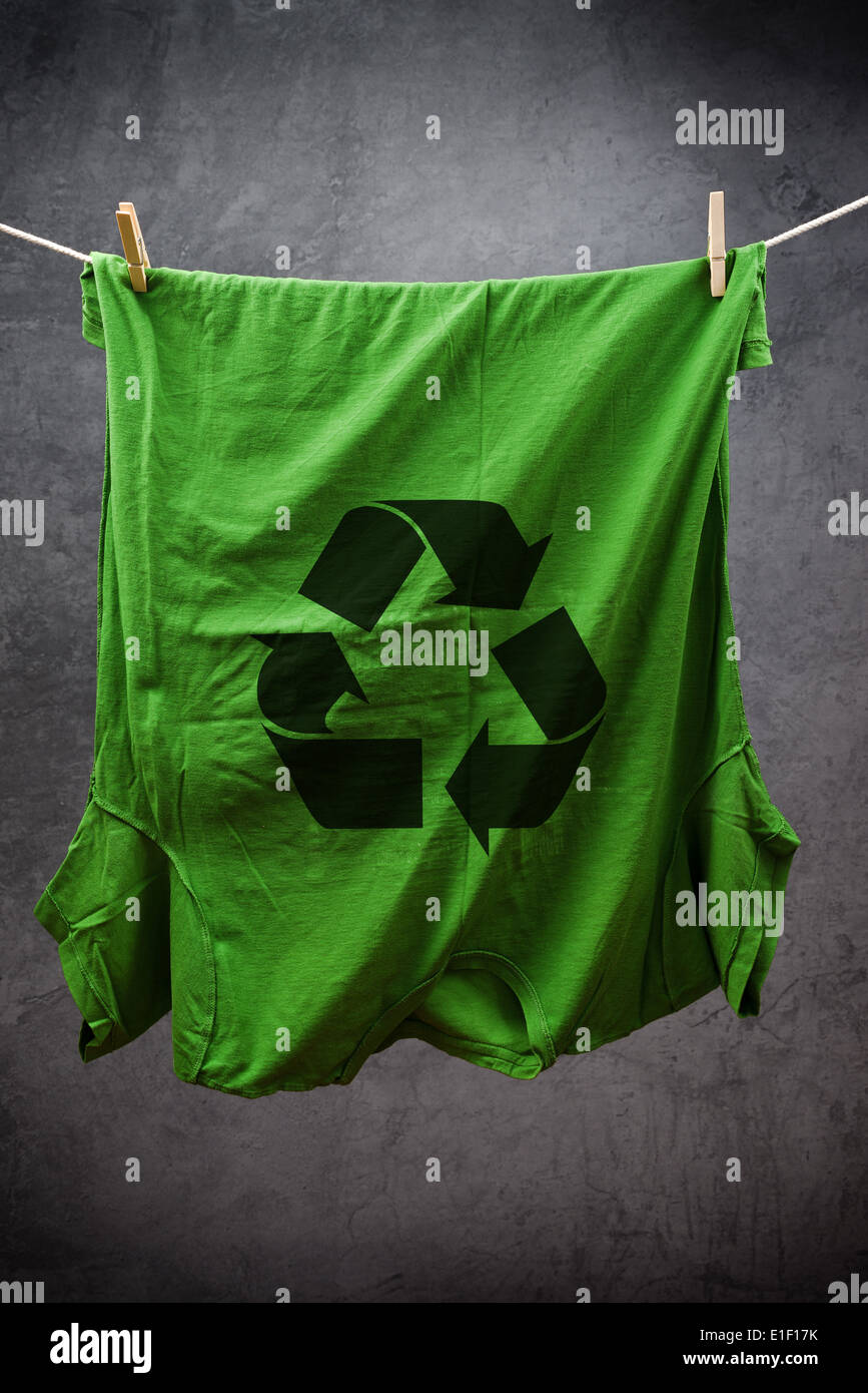 Grünes t-Shirt mit Recycling-Symbol hängen am Seil zum Trocknen, mit Kleidung Stifte angebracht. Stockfoto