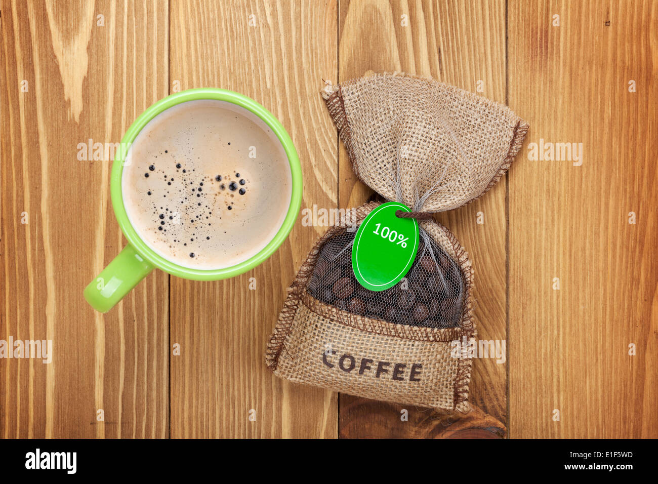 Kaffeetasse und kleine Tasche mit Bohnen auf Holztisch. Ansicht von oben Stockfoto
