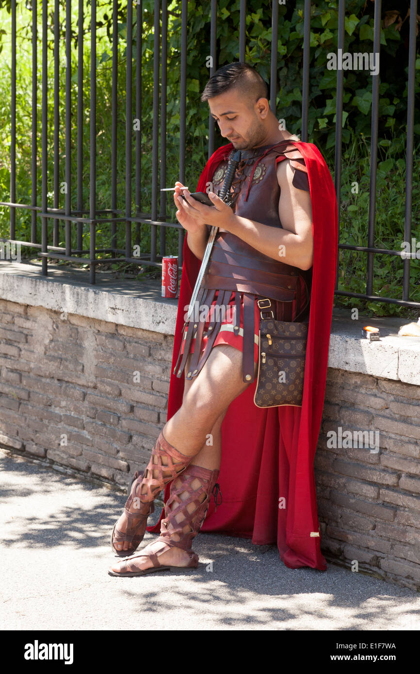 Ein Mann in römischer Soldat Kostüm ausziehen Zeit sein Handy benutzen, haben eine Zigarette und eine Dose Cola; Rom Italien Stockfoto