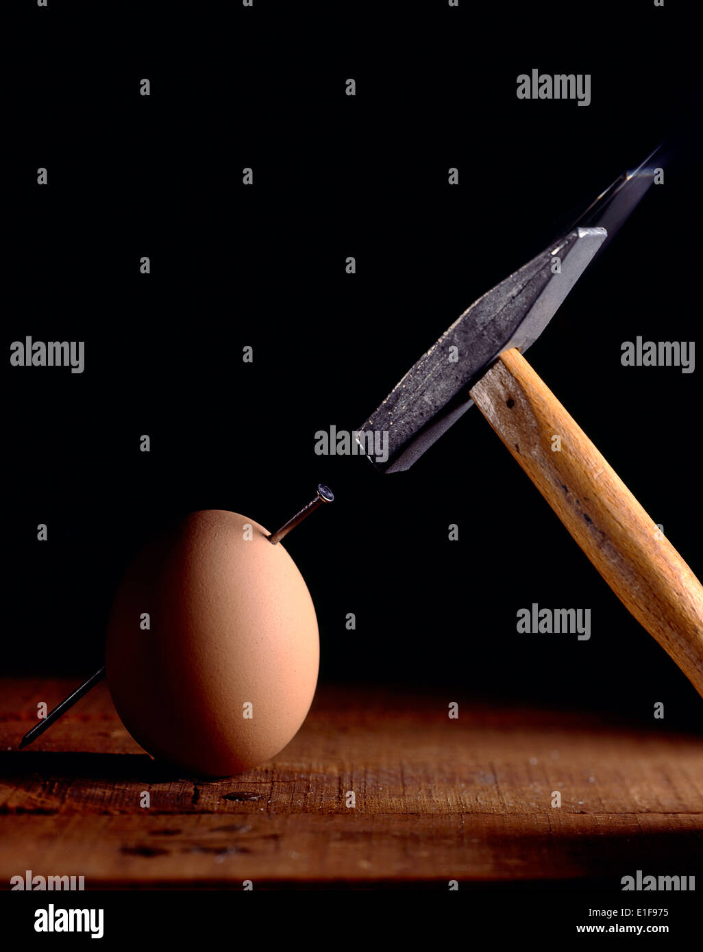 Ei mit Hammer auf Holzoberfläche genagelt Stockfoto