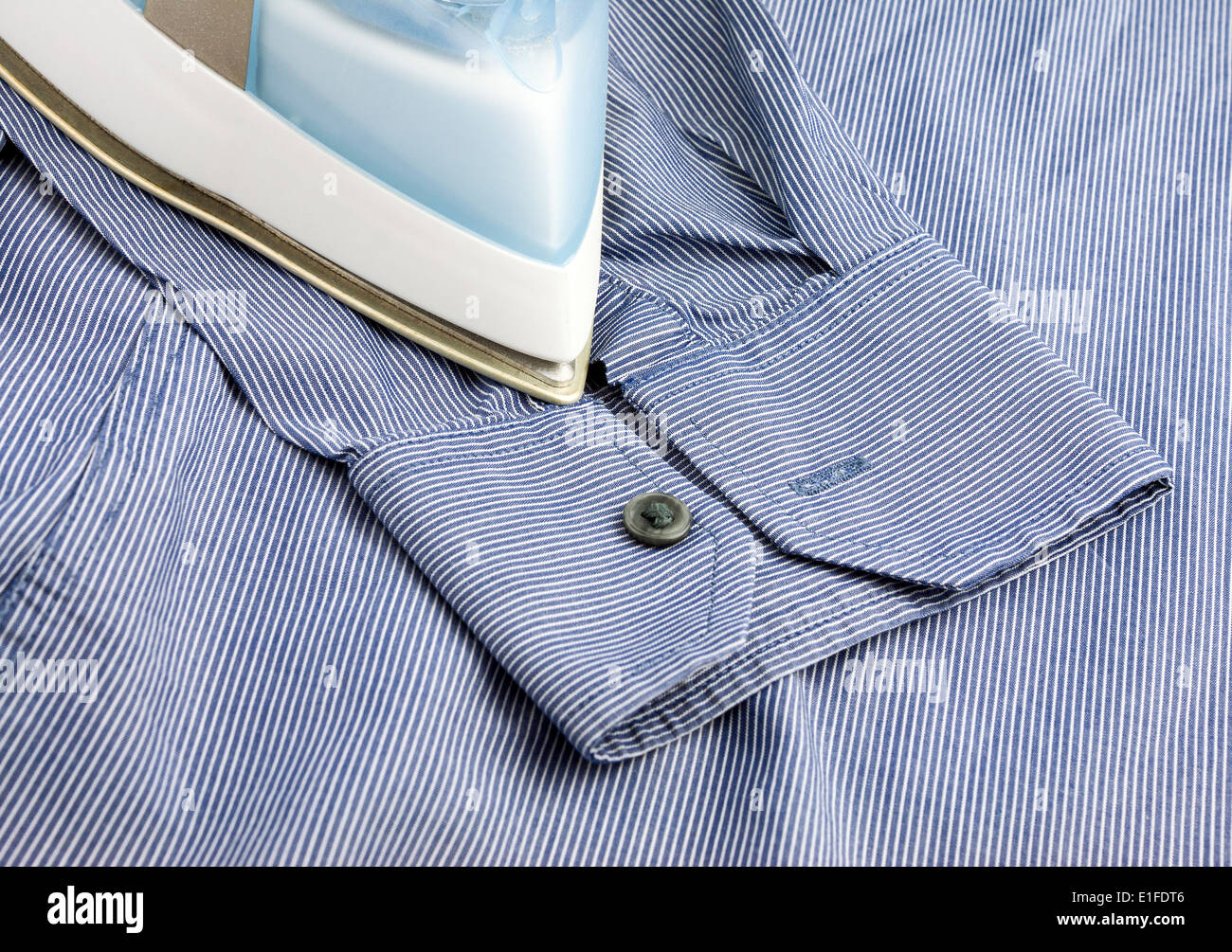 Teil des Dampfbügeleisens auf blaues Hemd Hintergrund Stockfoto