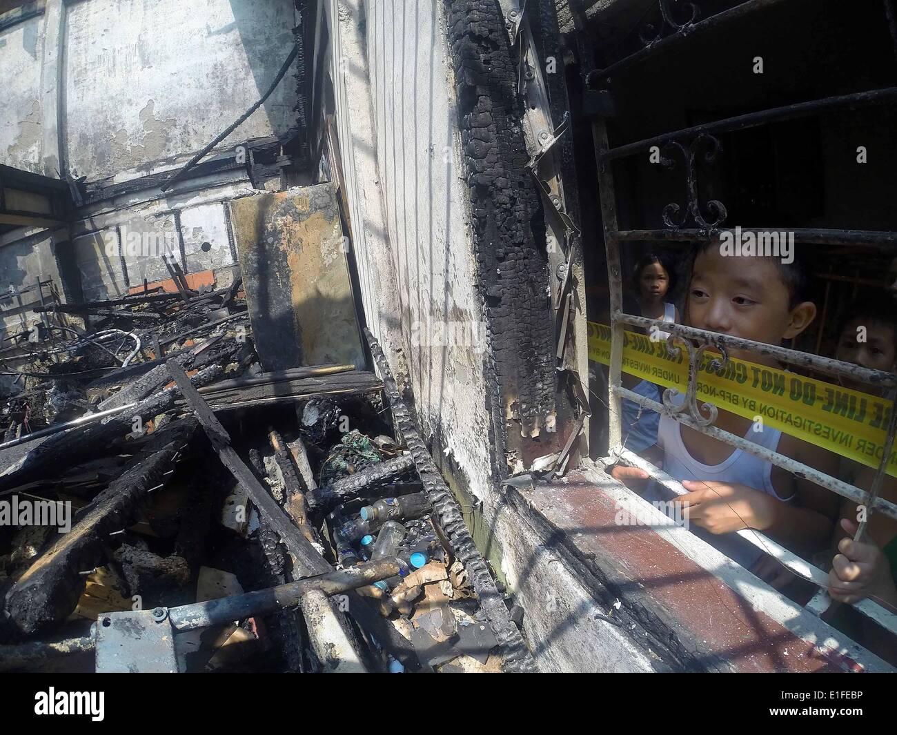 Manila, Philippinen. 3. Juni 2014. Kinder sehen in das verbrannte zweistöckige Gebäude in Manila, Philippinen, 3. Juni 2014. Fünf Menschen starben in dem Brandereignis wie Brandstiftung Ermittler die Ursache des Feuers untersuchen. Bildnachweis: Rouelle Umali/Xinhua/Alamy Live-Nachrichten Stockfoto