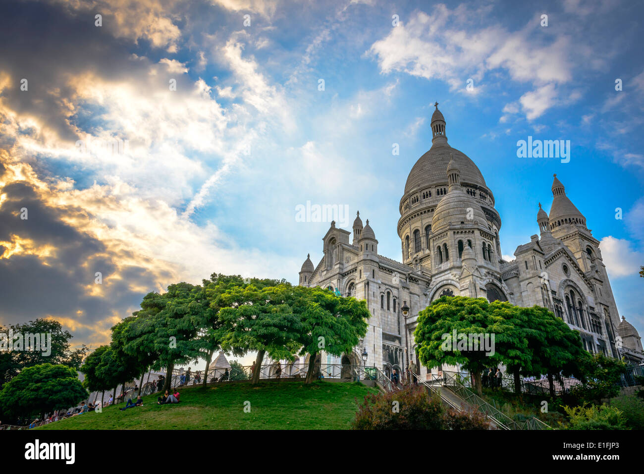 Basilika Sacré-Cœur kurz vor Sonnenuntergang mit Menschen sitzen auf dem Rasen im Quadrat Louise Michel Stockfoto