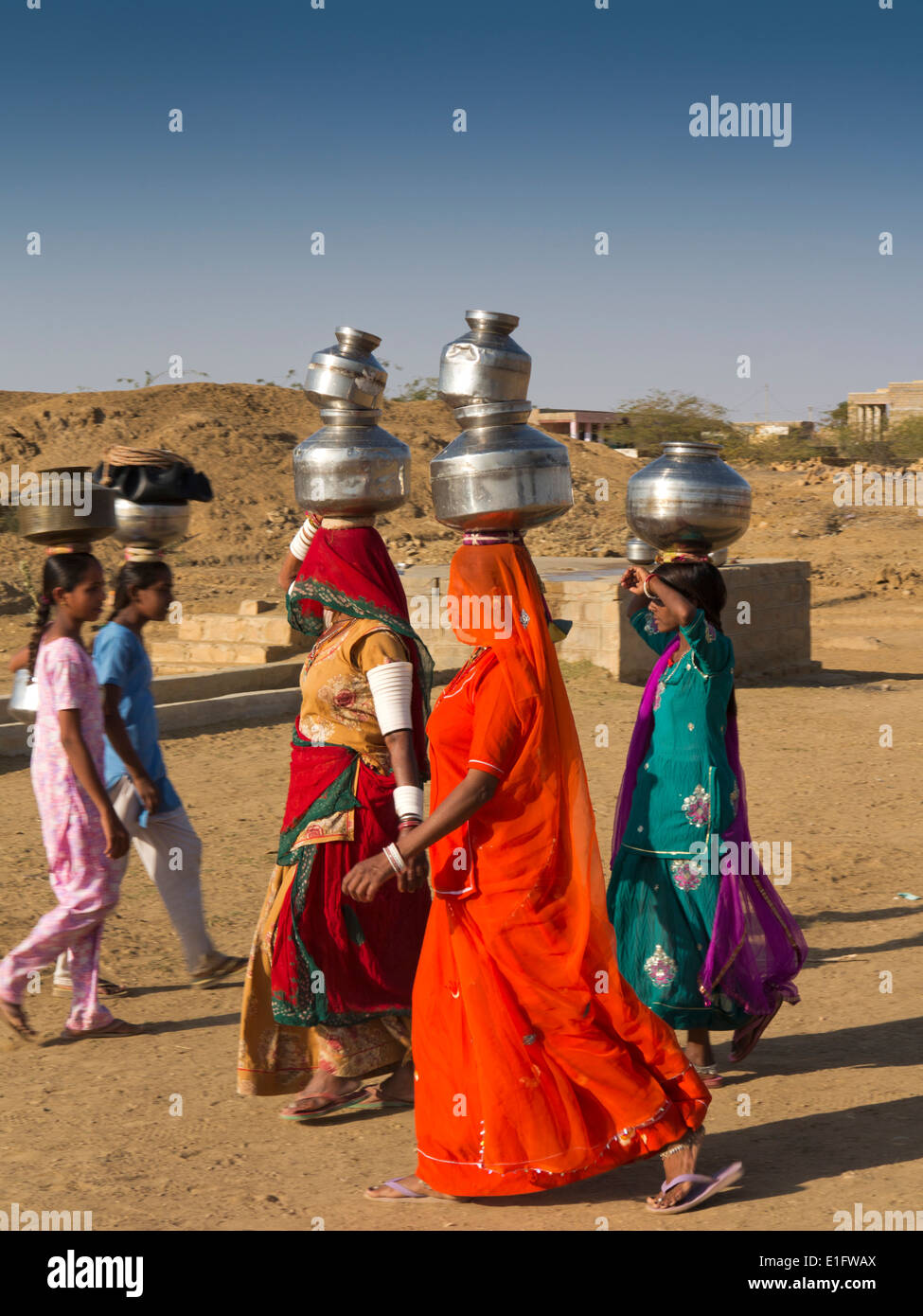 Indien, Rajasthan, Jaisalmer, Thar-Wüste, Khuri, Frauen in bunten Saris Wassertragen vom Dorf gut gekleidet Stockfoto