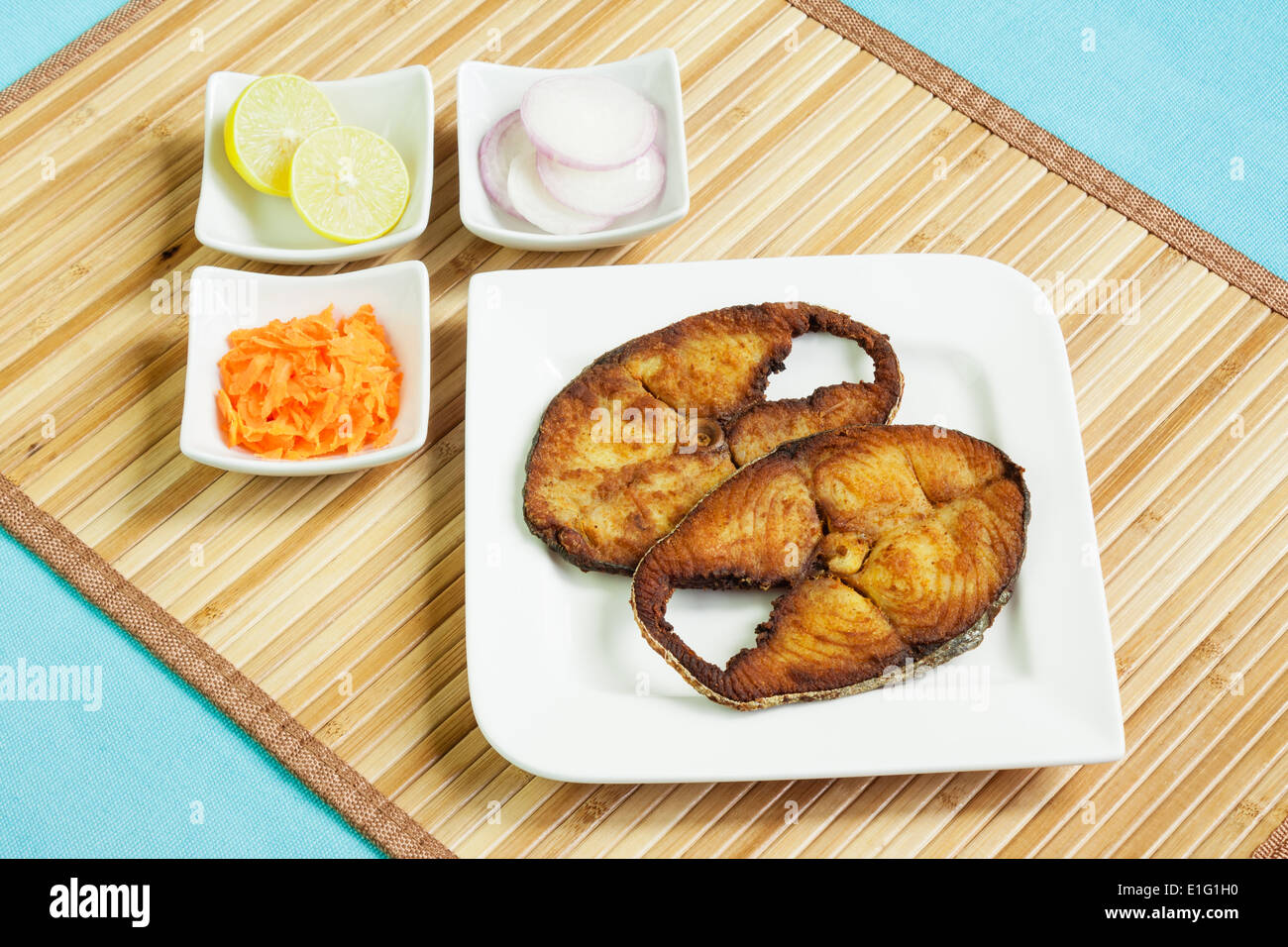 Lecker, knusprig gebratene, verkrusteten Seher/Makrele Fischfilets mit geriebenen Karotten, rohe Zwiebelringe und Zitrone serviert. Stockfoto