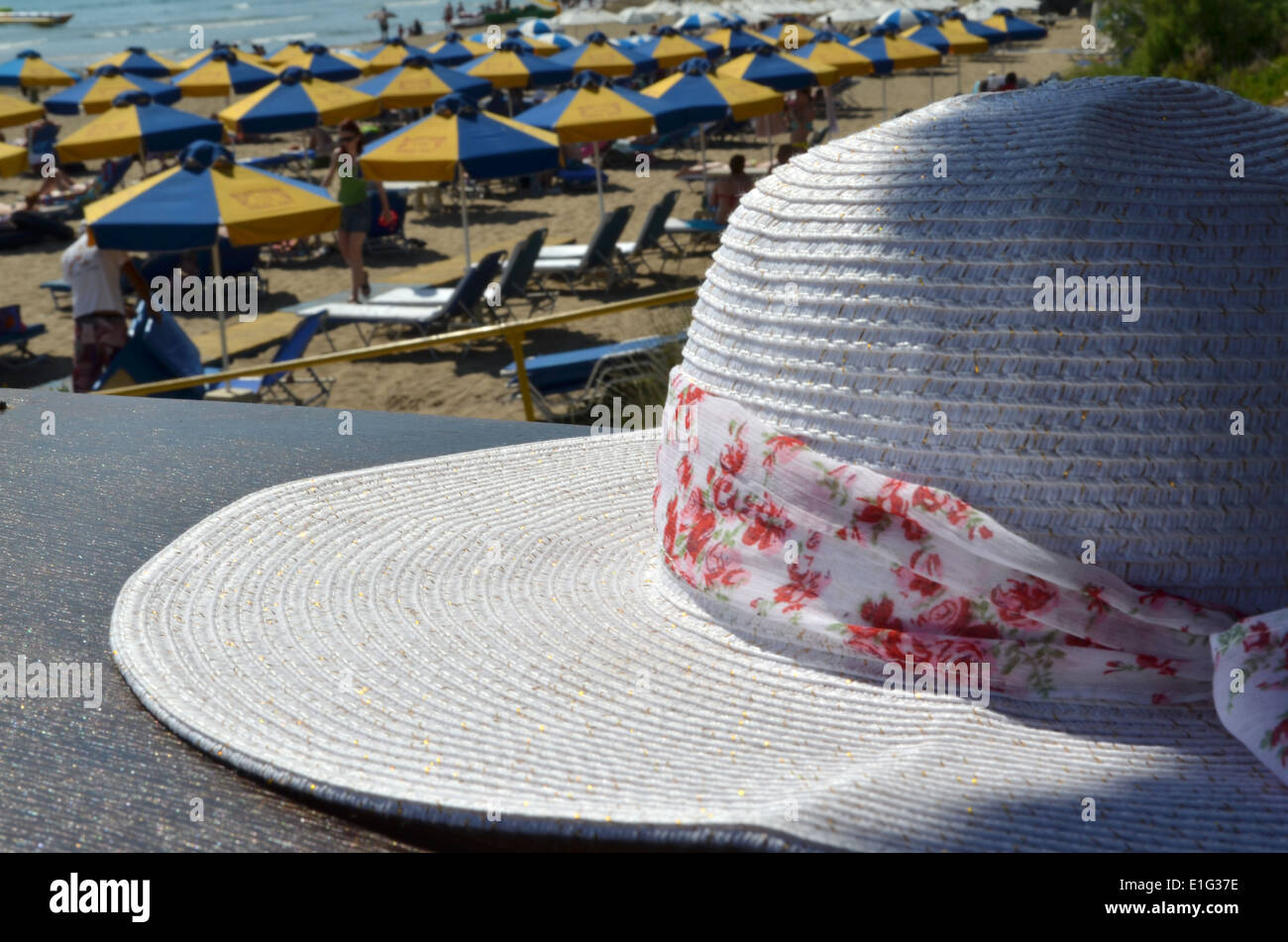 Weißer Sonnenhut mit floralen Band und goldenen Fäden auf Picknicktisch am Strand von Coral Bay, Zypern Stockfoto