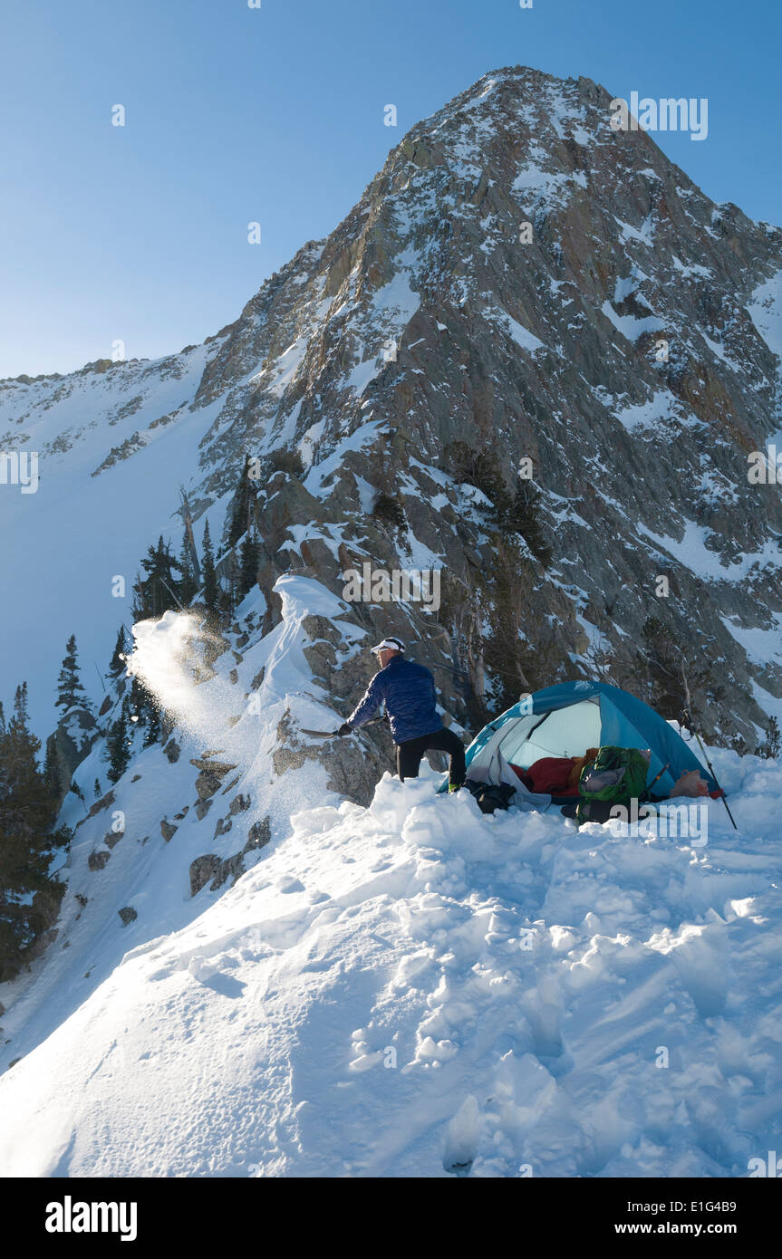 Ein Mann, Schnee Schaufeln, während camping unterhalb der Pfeiffferhorn in Lone Peak Wilderness, Salt Lake City, Utah. Stockfoto