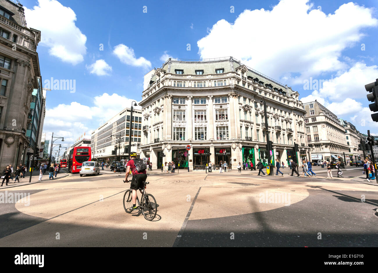 Ein Radfahrer, der sein Fahrrad durch Oxford Circus, London, England, Großbritannien fährt. Stockfoto