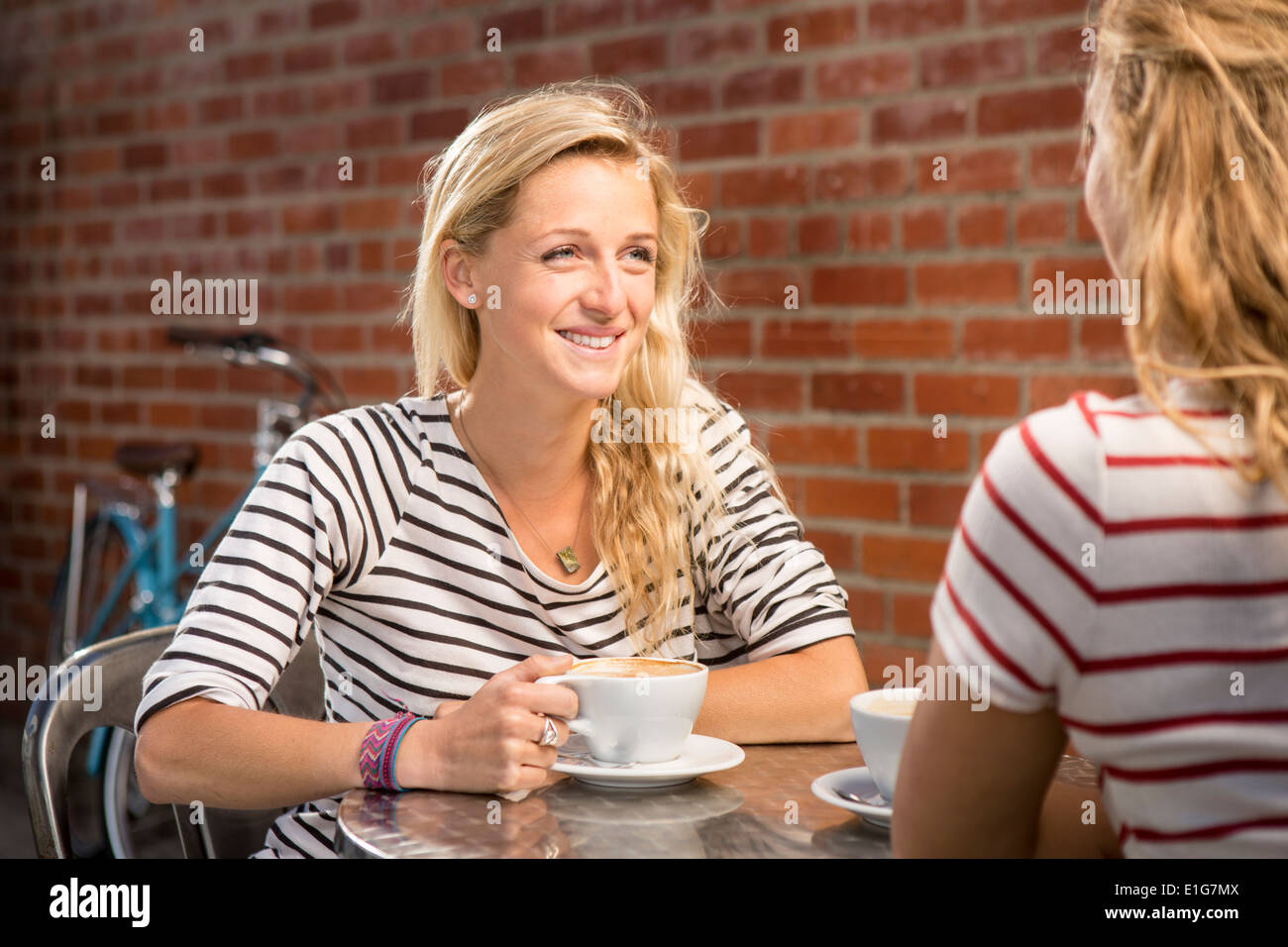 Nahaufnahme von zwei Frauen in den Zwanzigern eine Pause von ihrer Radtour, Kaffee zusammen. Stockfoto