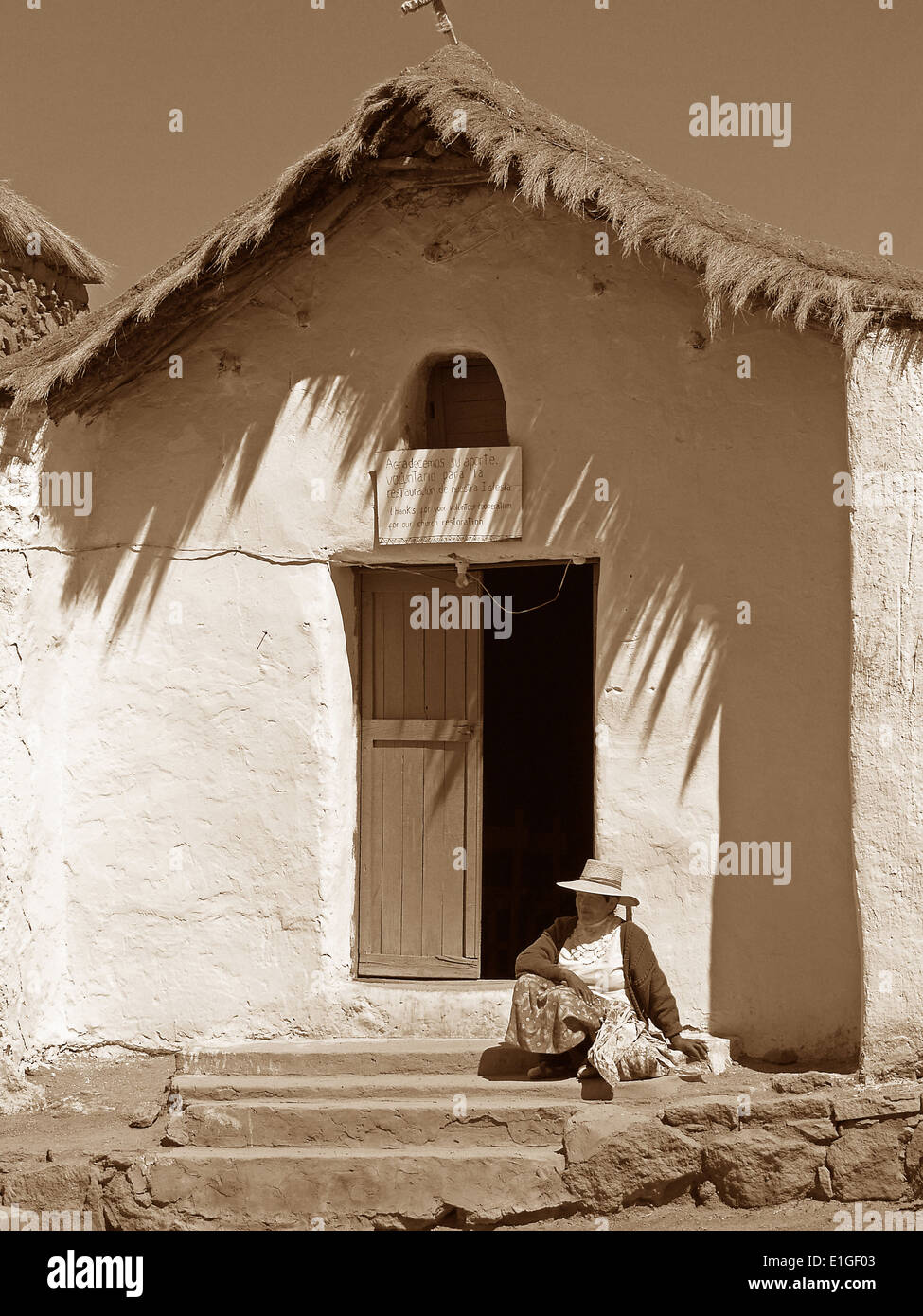 Eine Atacapeno Frau sitzt vor der Iglesia San Carlos im Dorf Machuca, Atacamawüste, Chile Stockfoto