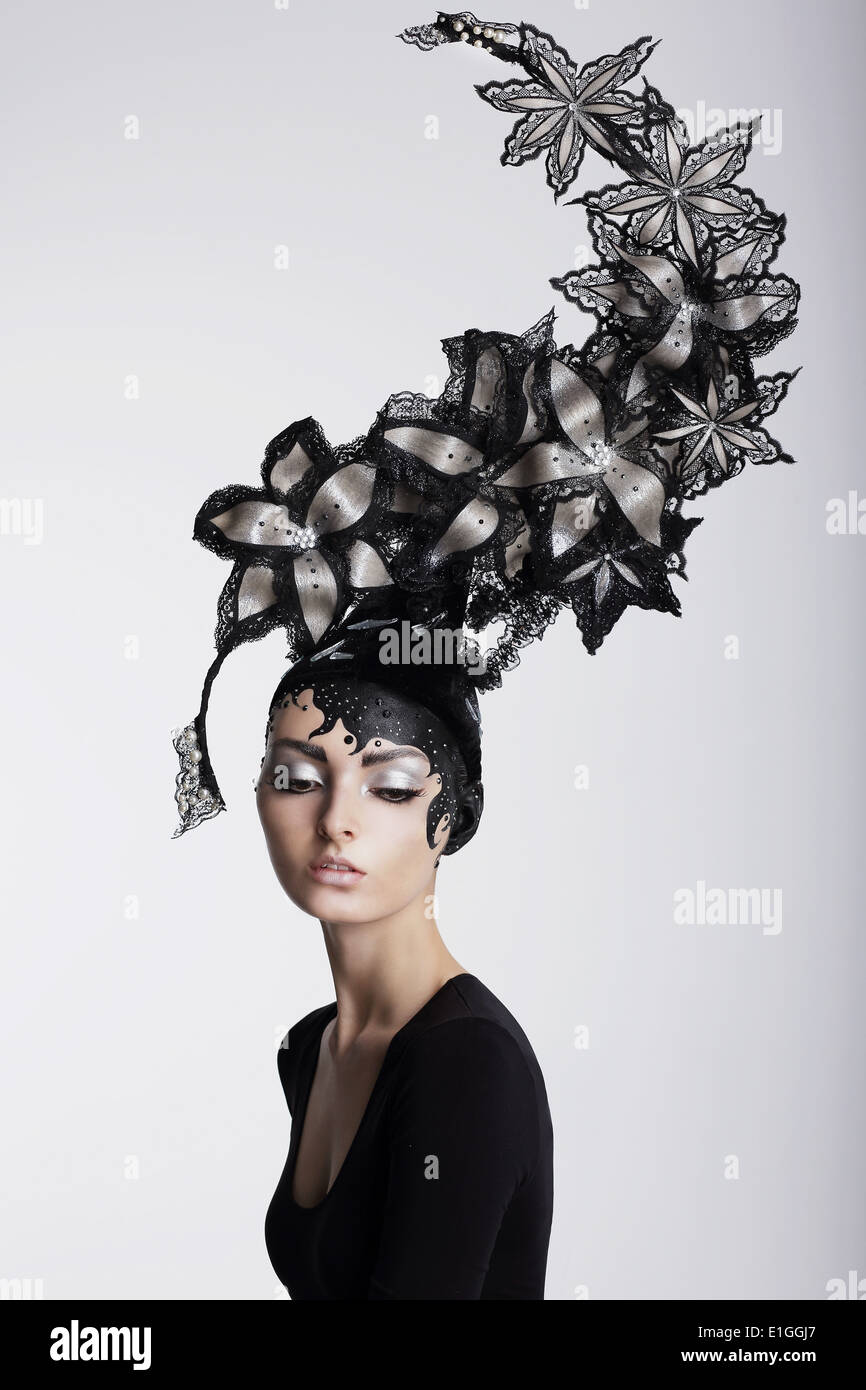 Fantasie. Surrealismus. Erstaunliche Frau in trendige Kopfbedeckung mit Blumen Stockfoto