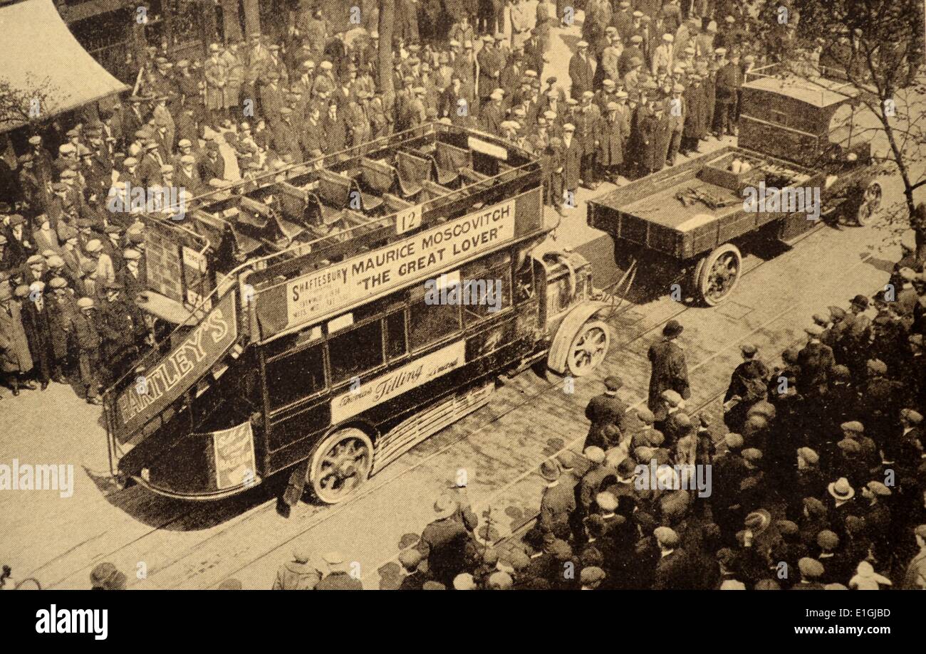 Eine Menschenmenge schaut zu, wie eine frühe Ära London Bus wird nach Leiden Motorprobleme geschleppt. 1920 Stockfoto