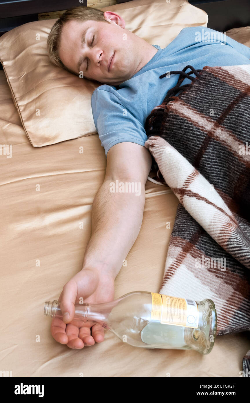 Junger Mann schlafen auf der Couch mit einer Flasche wiskey Stockfoto