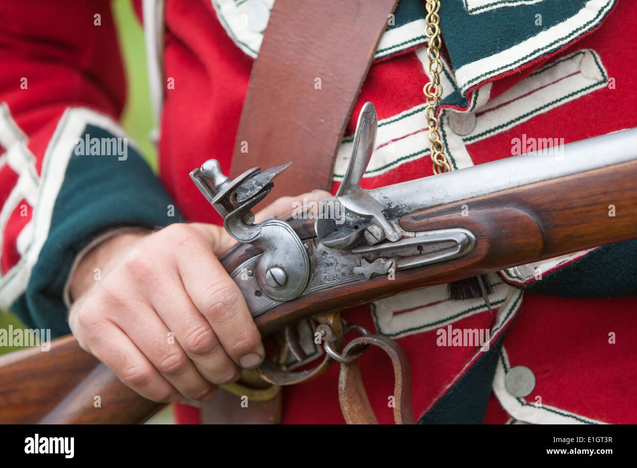 Ein Soldat gekleidet in traditionellen 17. Jahrhundert englische Armee Rotrock einheitliche laden eine Steinschlossmuskete. Stockfoto