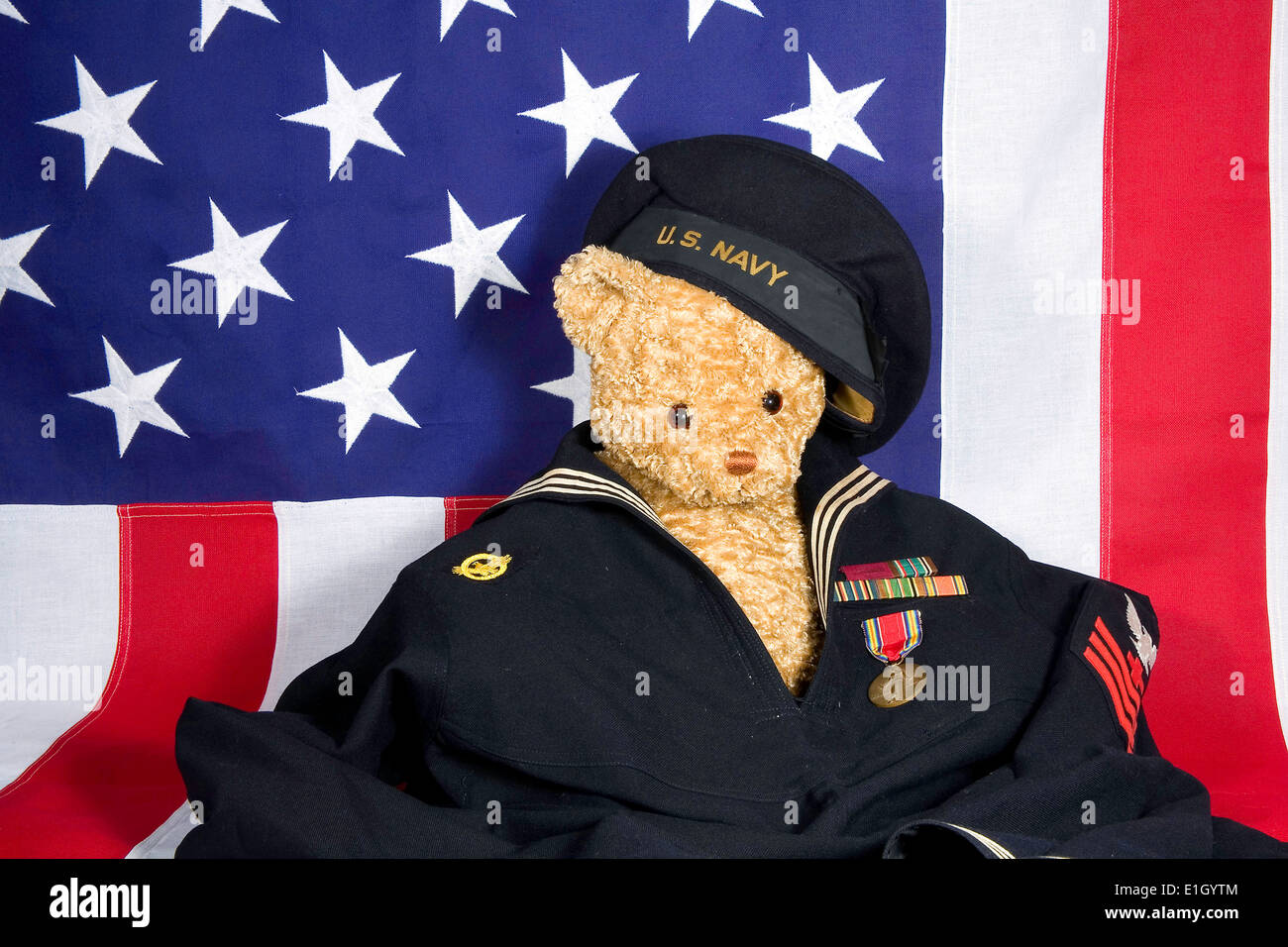 Teddybär in WWII Marine uniform mit Metallen vor einer amerikanischen Flagge. Stockfoto