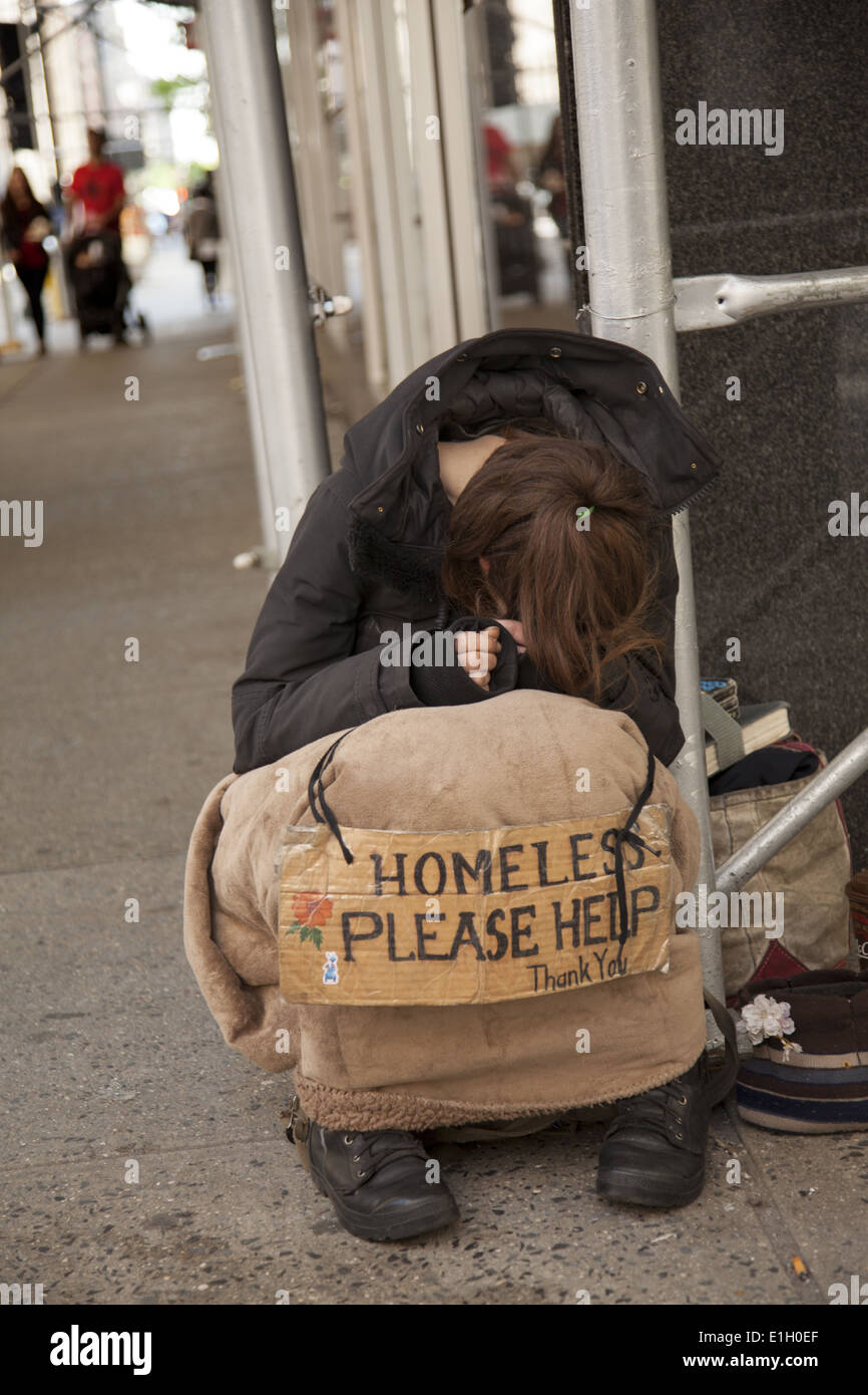 Junge Obdachlose streckt mit einem Schild auf dem Bürgersteig in Midtown Manhattan. Stockfoto