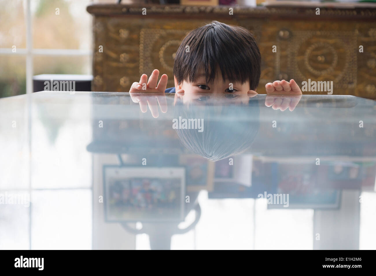 Porträt eines jungen peeking über Esstisch Stockfoto
