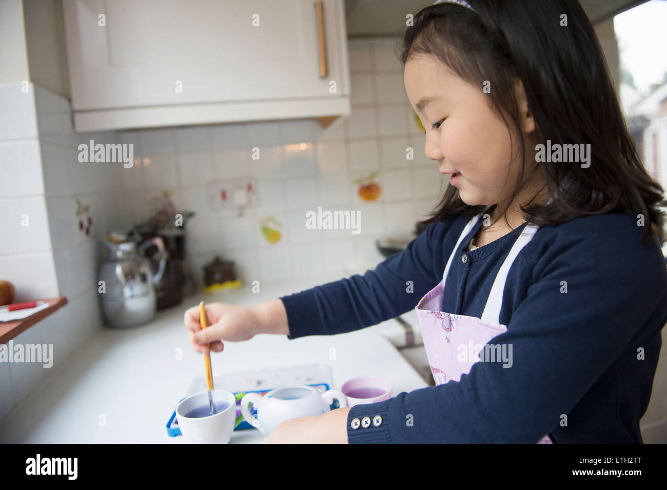 Junges Mädchen Tauchen Pinsel in der Wasserschale in Küche Stockfoto