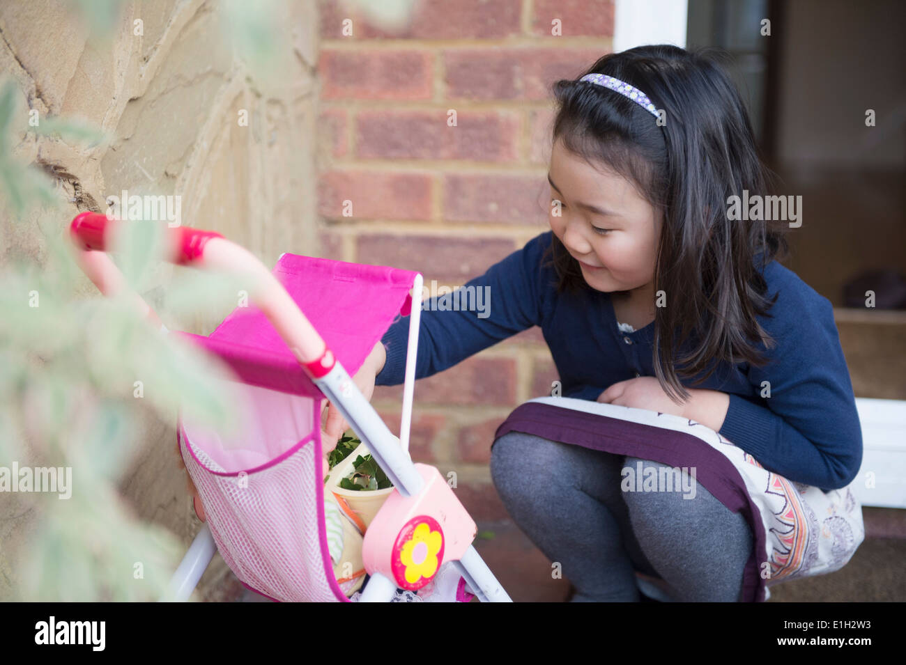 Junge Mädchen spielen mit Spielzeug Kinderwagen Stockfoto