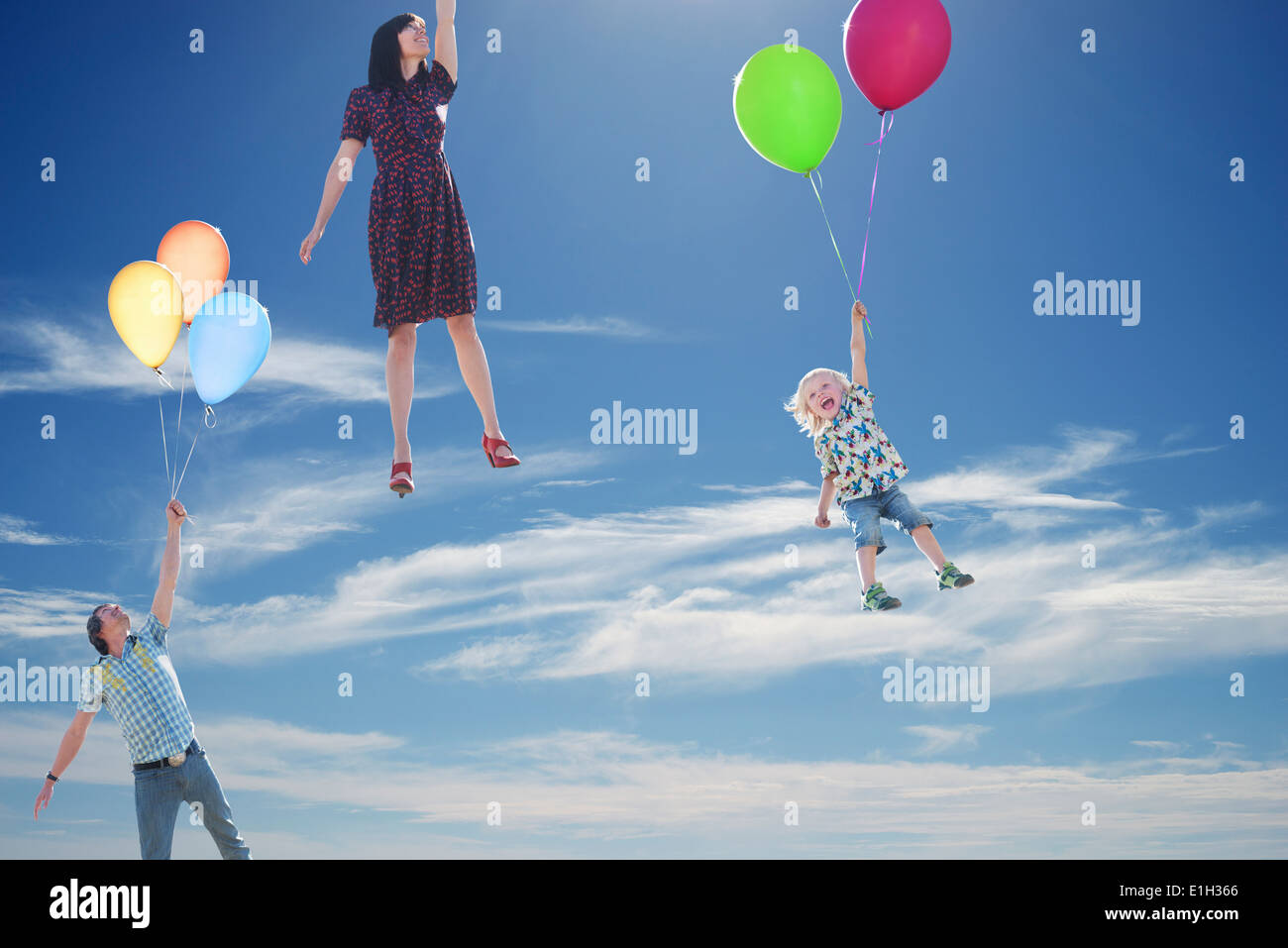 Älteres Paar und seinem kleinen Sohn himmelwärts festhalten an Ballons schweben Stockfoto