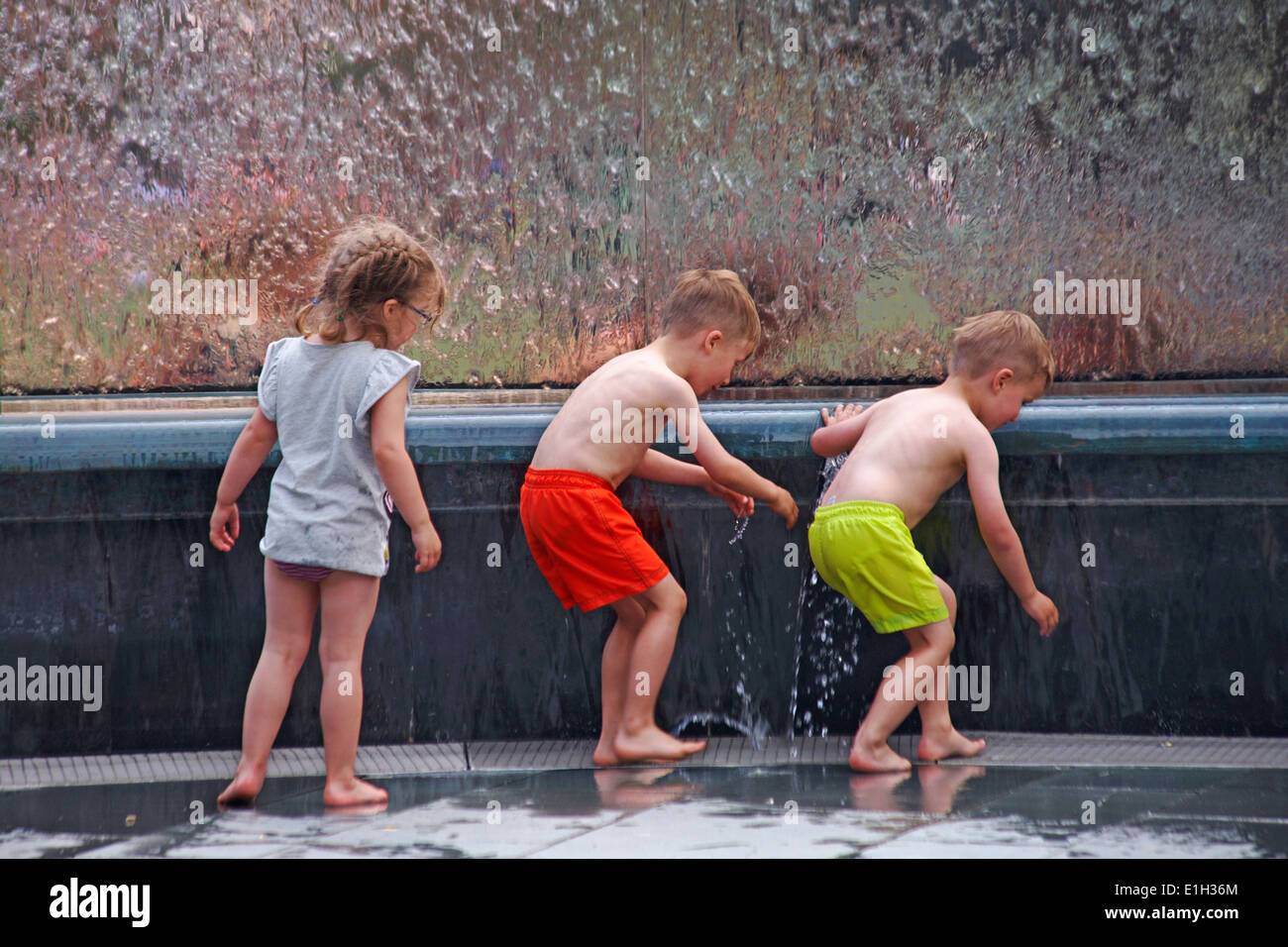genießen das Wasser - Kinder spielen im Wasserbrunnen im Millenium Square, Harbourside, Bristol im Mai Stockfoto