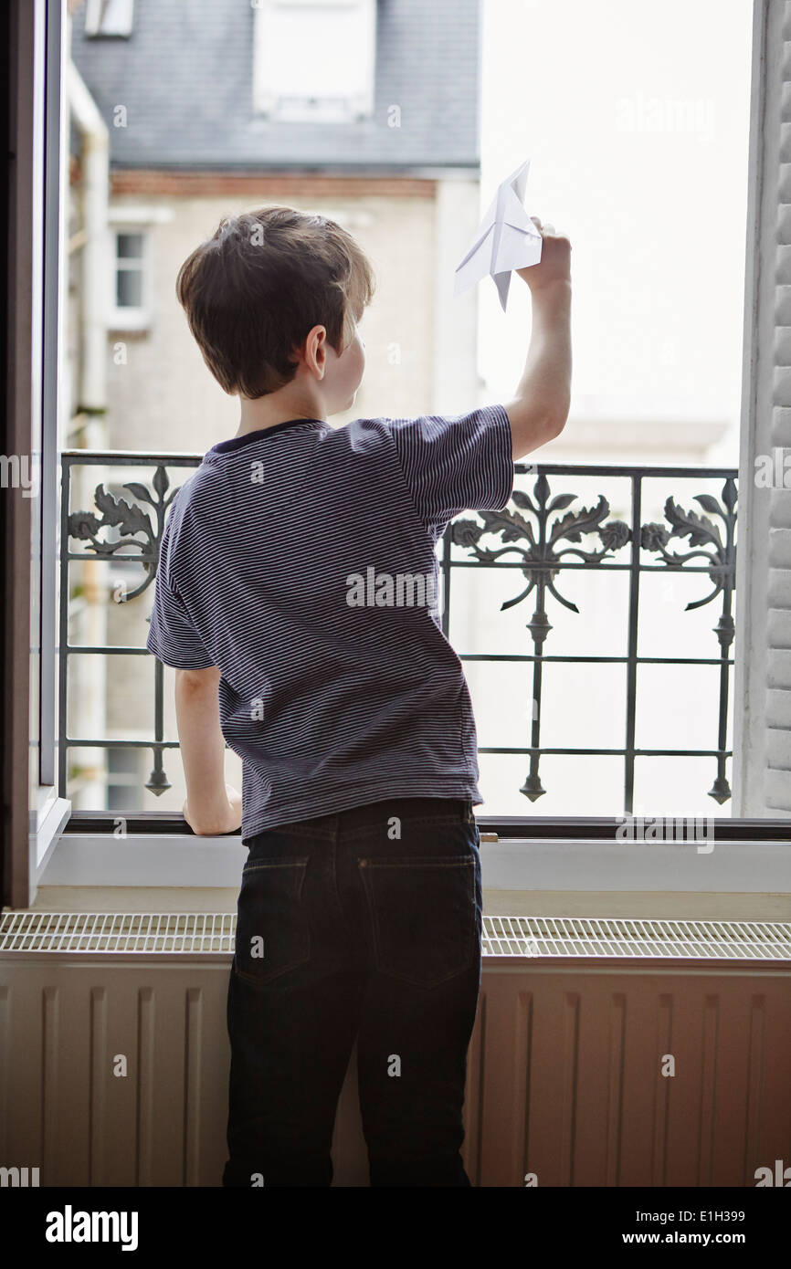 Junge Papierflieger aus Fenster starten Stockfoto