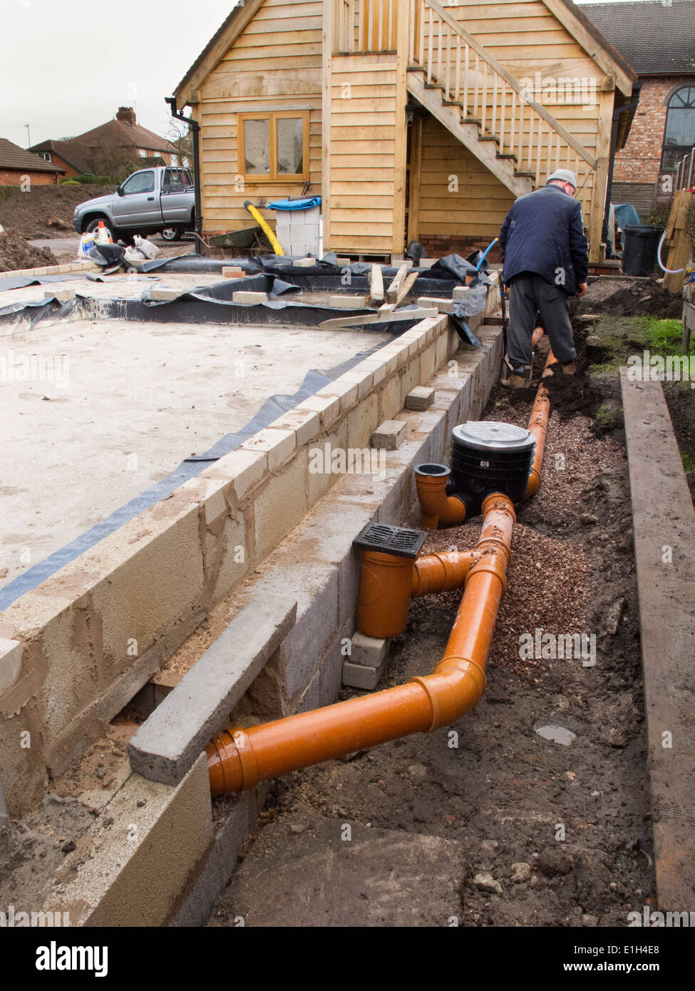 Selbstbau-Haus, Entwässerung, Mann macht Abfluss-Rohrverbindung zum Rinnen Stockfoto