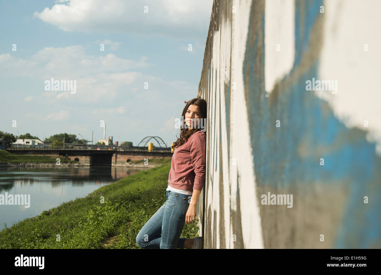 Junge Frau, die Wand gelehnt Stockfoto