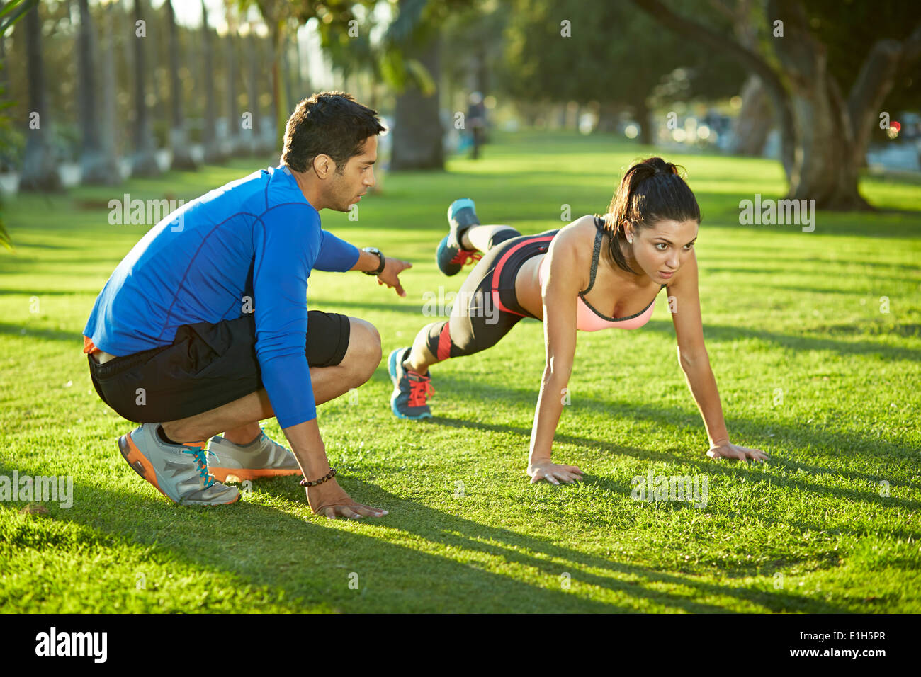 Personal Trainer mit Frau Plank Übung Stockfoto