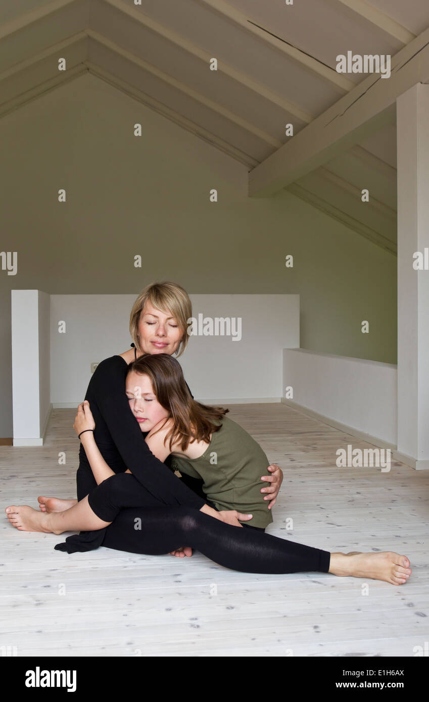 Mutter und zwölf Jahre alte Tochter umarmt Erdgeschoss Stockfoto