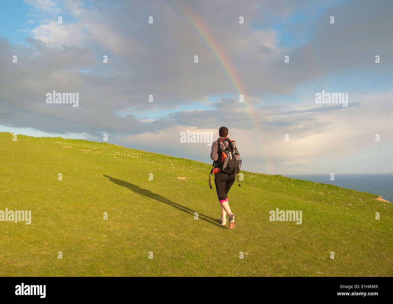 Junge weibliche Wanderer, Wandern bergauf in Richtung Regenbogen Stockfoto