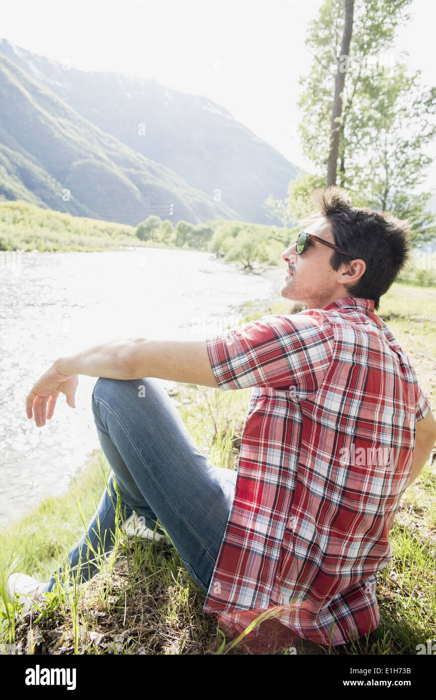 Junger Mann sitzt auf Toce Flussufer, Piemont, Italien Stockfoto