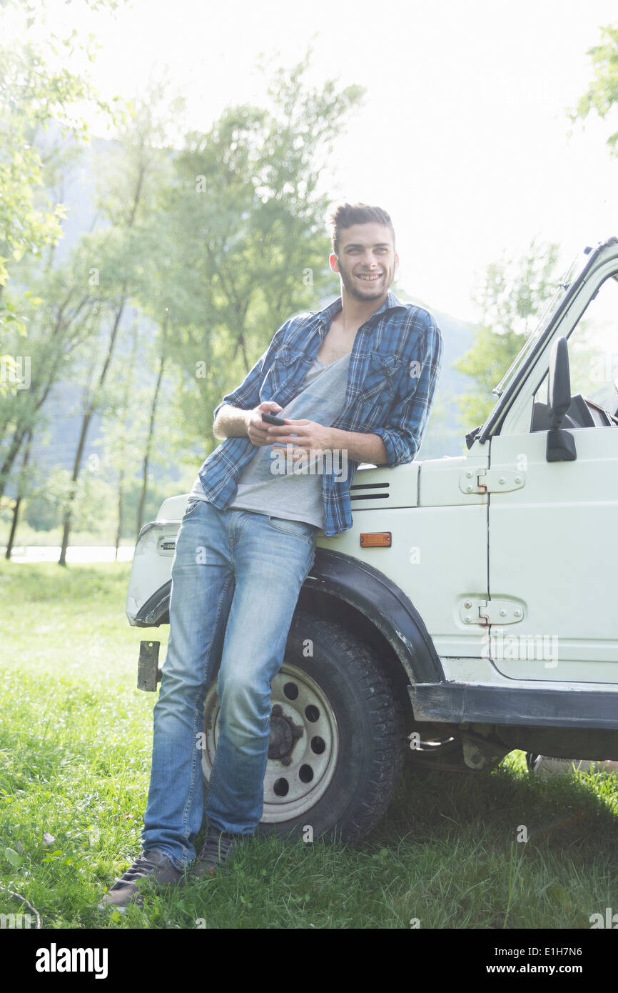 Junger Mann lehnte sich gegen Geländewagen Stockfoto