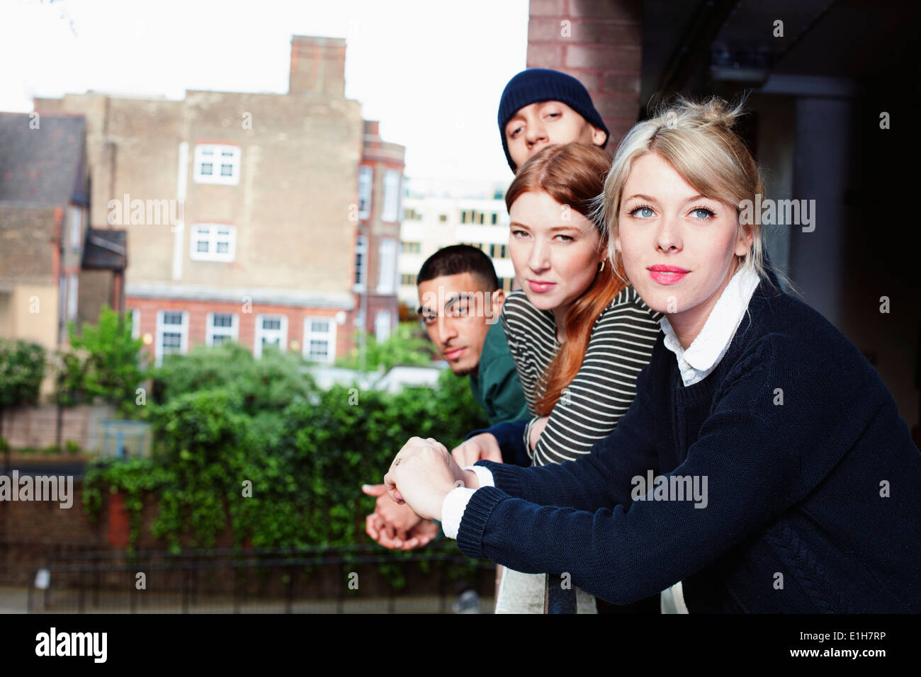 Vier junge Erwachsene, stehend auf Balkon in London, UK Stockfoto