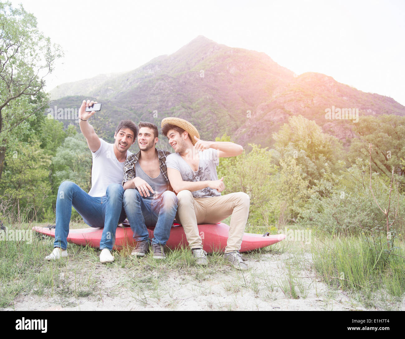 Drei junge Männer sitting on Top of Kanu, Selbstporträt Foto Stockfoto