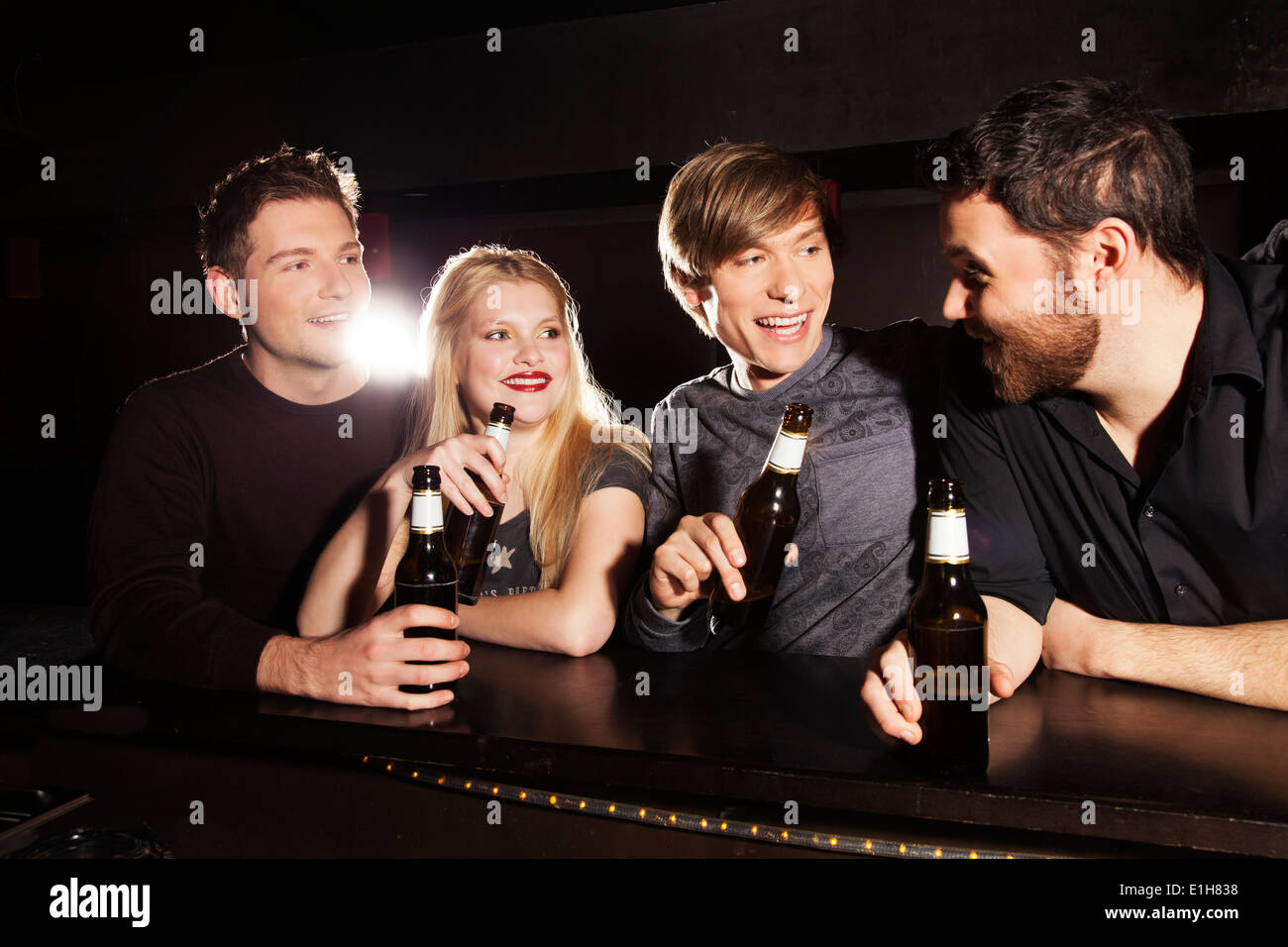 Vier Freunde trinken Flaschenbier in Nachtclub Stockfoto