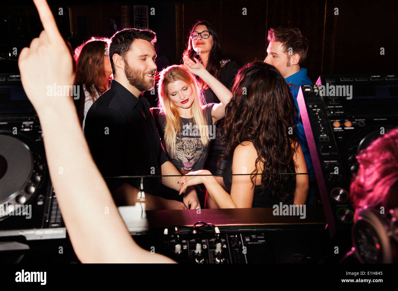 Gruppe junger Männer und Frauen tanzen vor DJ in Nachtclub Stockfoto