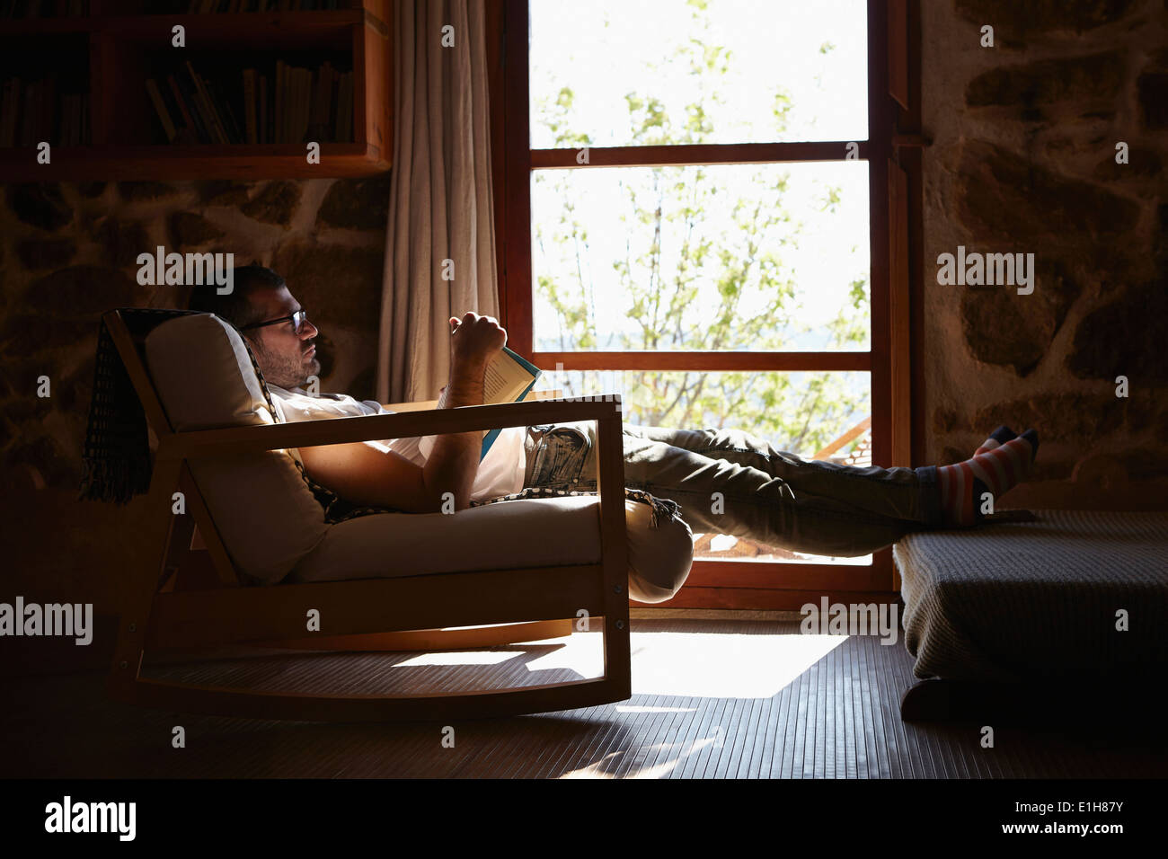 Mitte erwachsenen Mannes Buch zu lesen, während Sie im Wohnzimmer entspannen Stockfoto