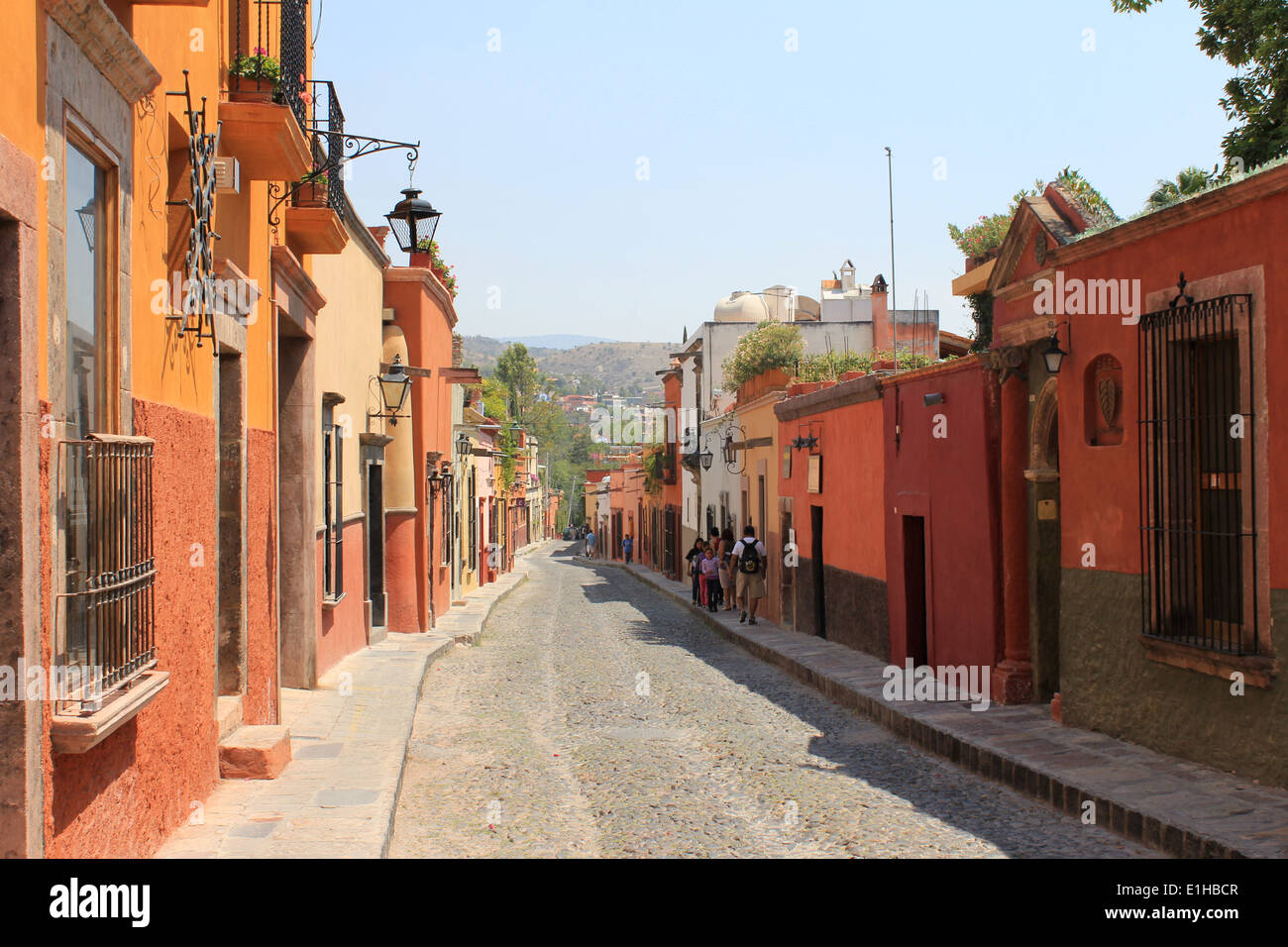 Bunte Häuser, die entlang einer gepflasterten Straße in San Miguel de Allende, Guanajuato, Mexiko Stockfoto