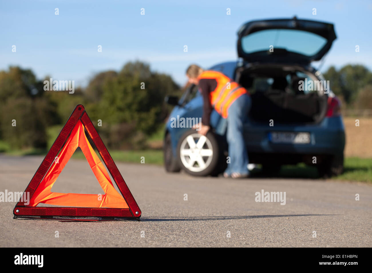 Reifenwechsel auf einem aufgeschlüsselt Auto mit einem roten Warndreieck Stockfoto