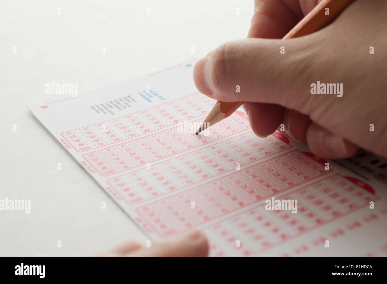Person markieren Zahl auf Lottoschein mit Stift Stockfoto
