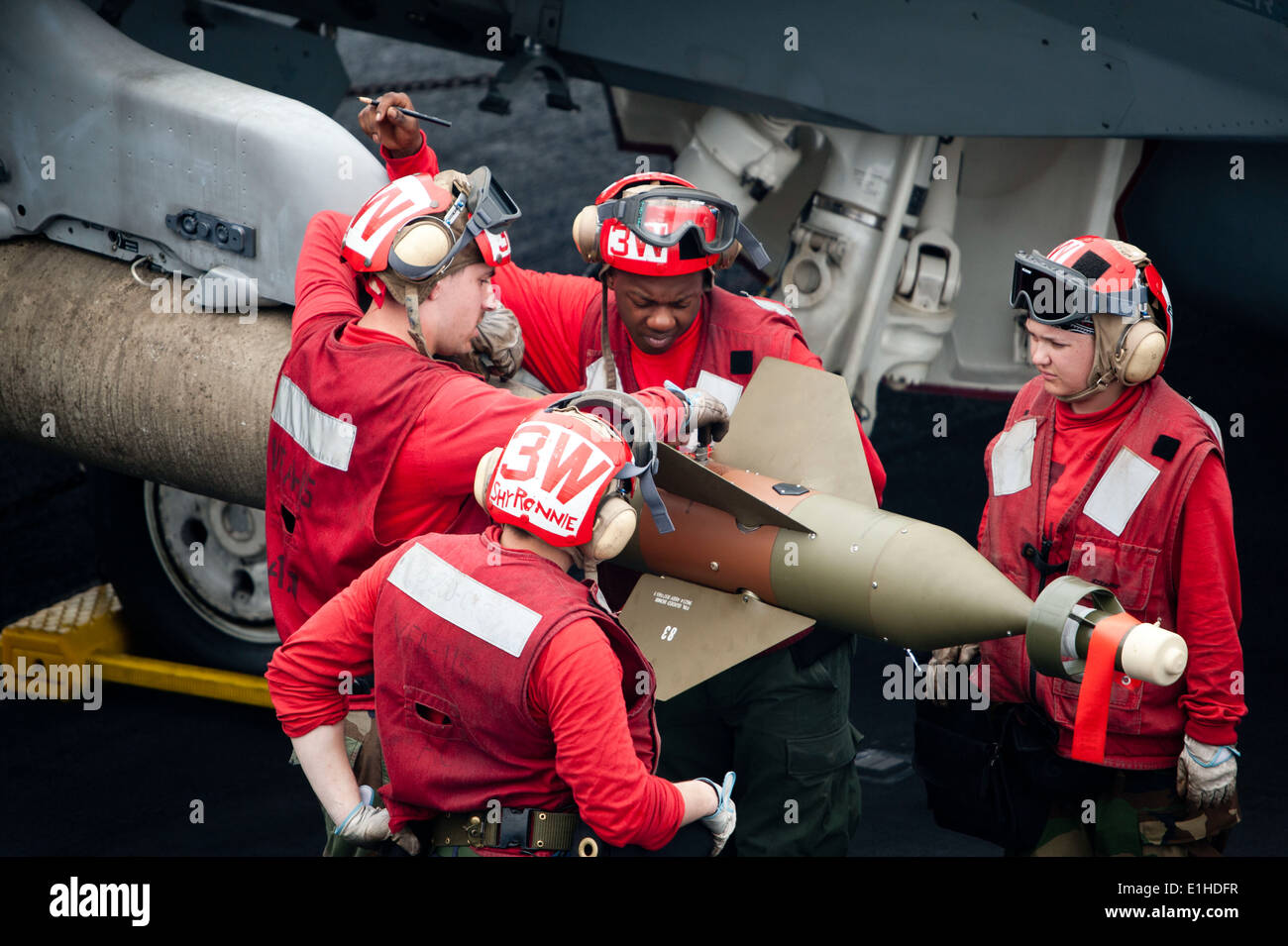 US Marine Aviation Ordnancemen zugewiesen Strike Fighter Squadron (VFA) 115 Arm eine GBU-16 Paveway II Bombe auf eine F/A-18E Super H Stockfoto