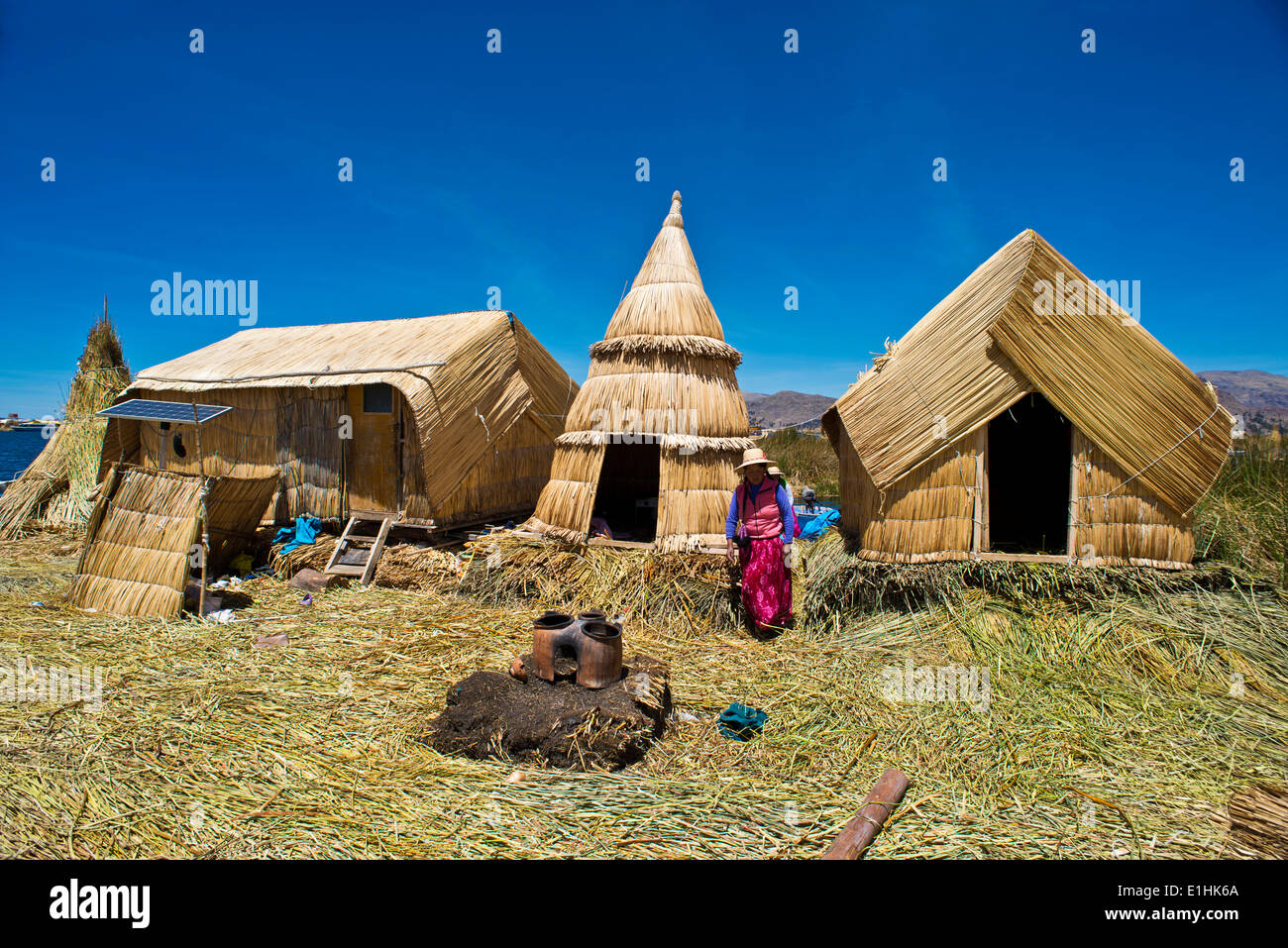 Frau des Uro-Indianer vor typischen Schilf Hütten, traditionellen Lehmofen im Vordergrund, machte schwimmenden Inseln von totora Stockfoto